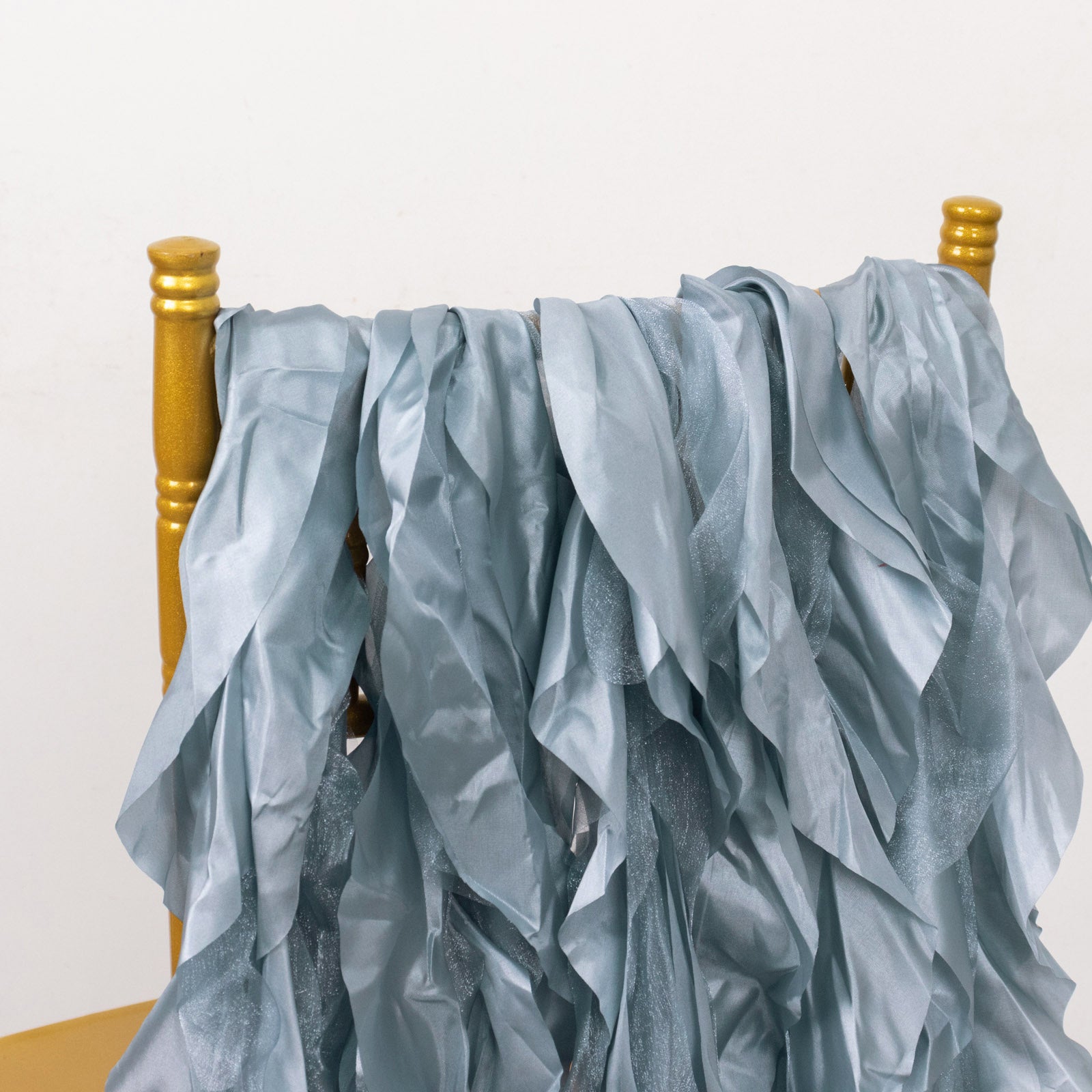 Dusty blue chiffon satin chair sashes draped on a gold chair.