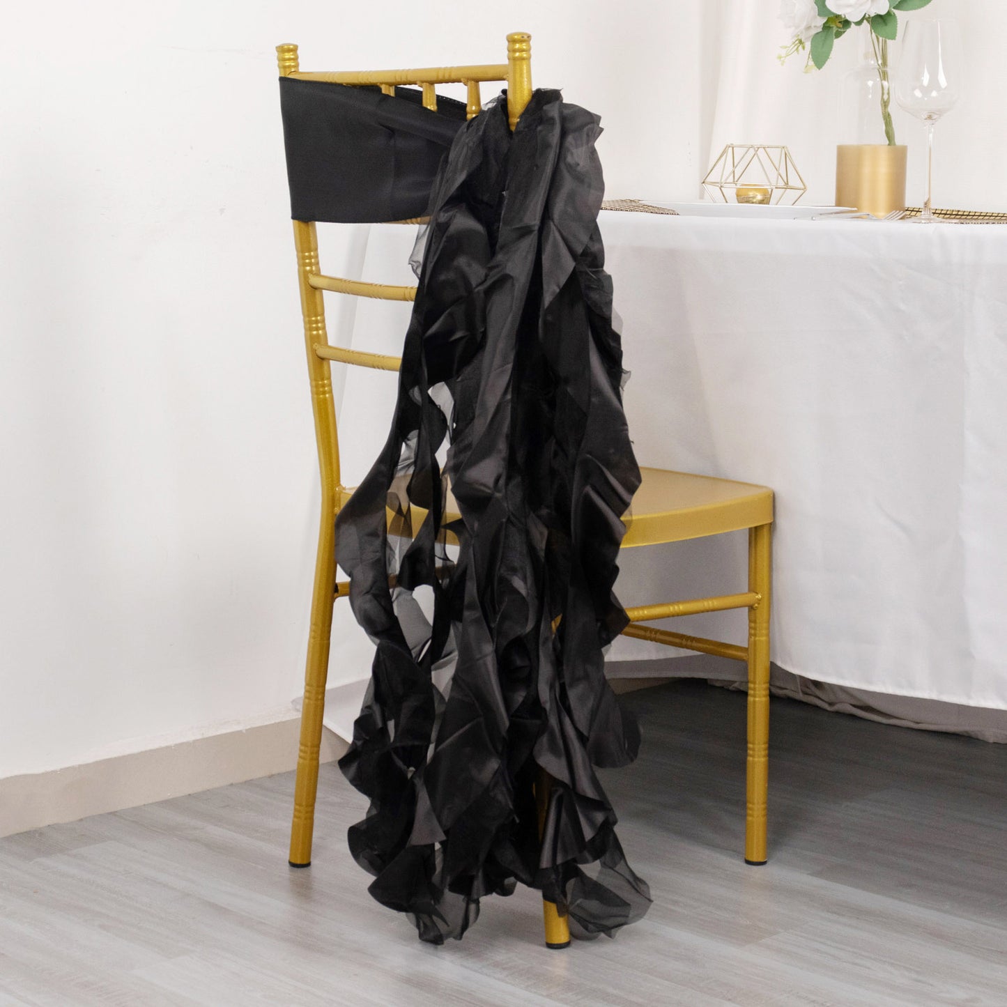Black curly chiffon satin chair sash draped over a gold chair.