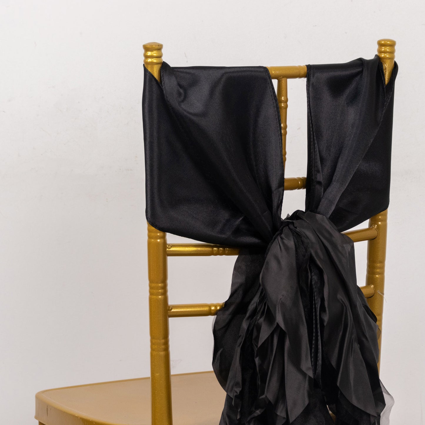 Black curly willow chiffon satin chair sashes on a gold chair.