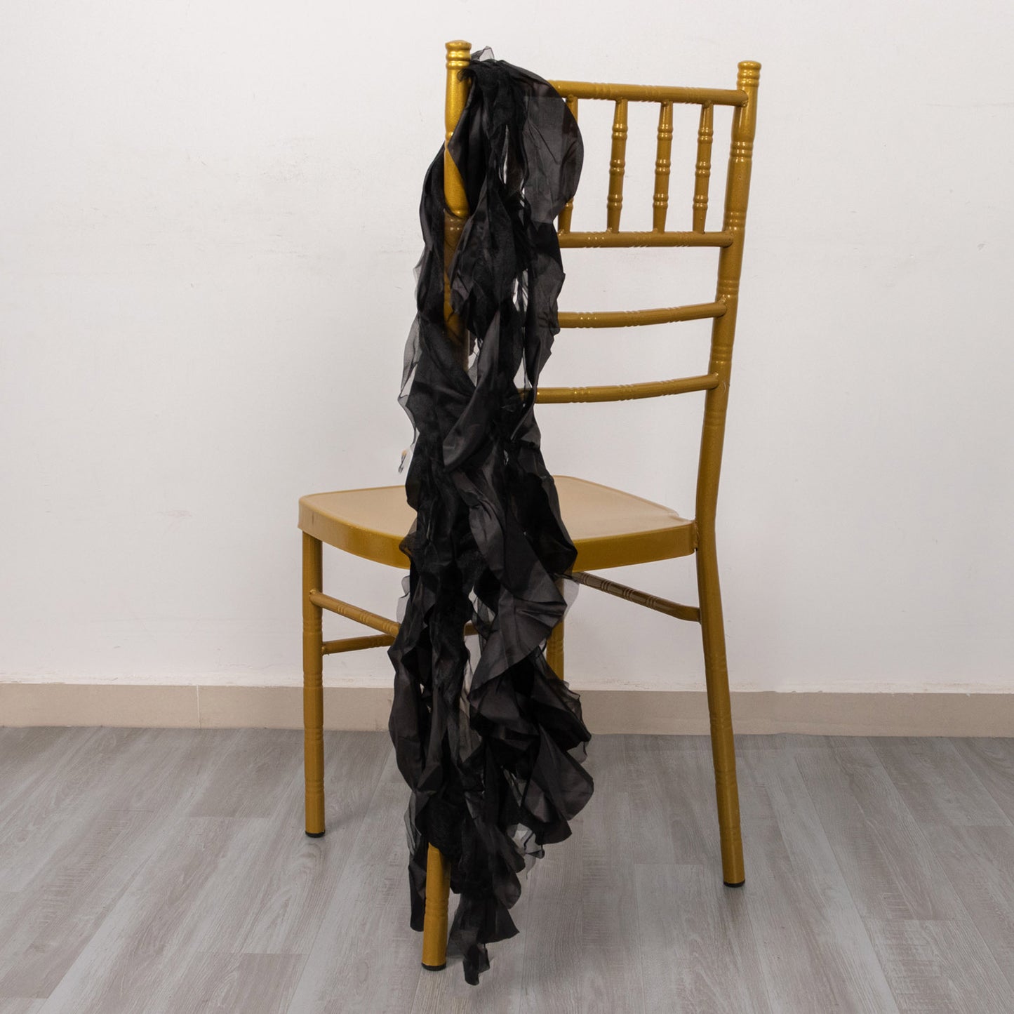 Black curly willow chiffon satin chair sash draped on a gold chair.