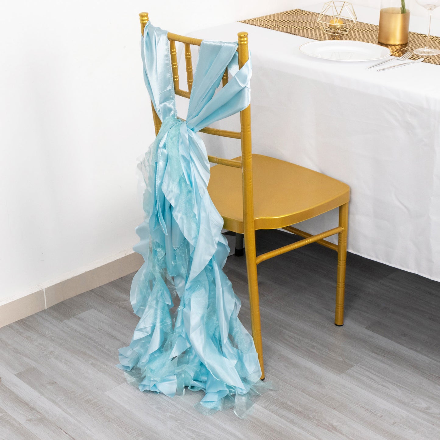 Light blue curly chiffon satin chair sash tied on a gold chair.