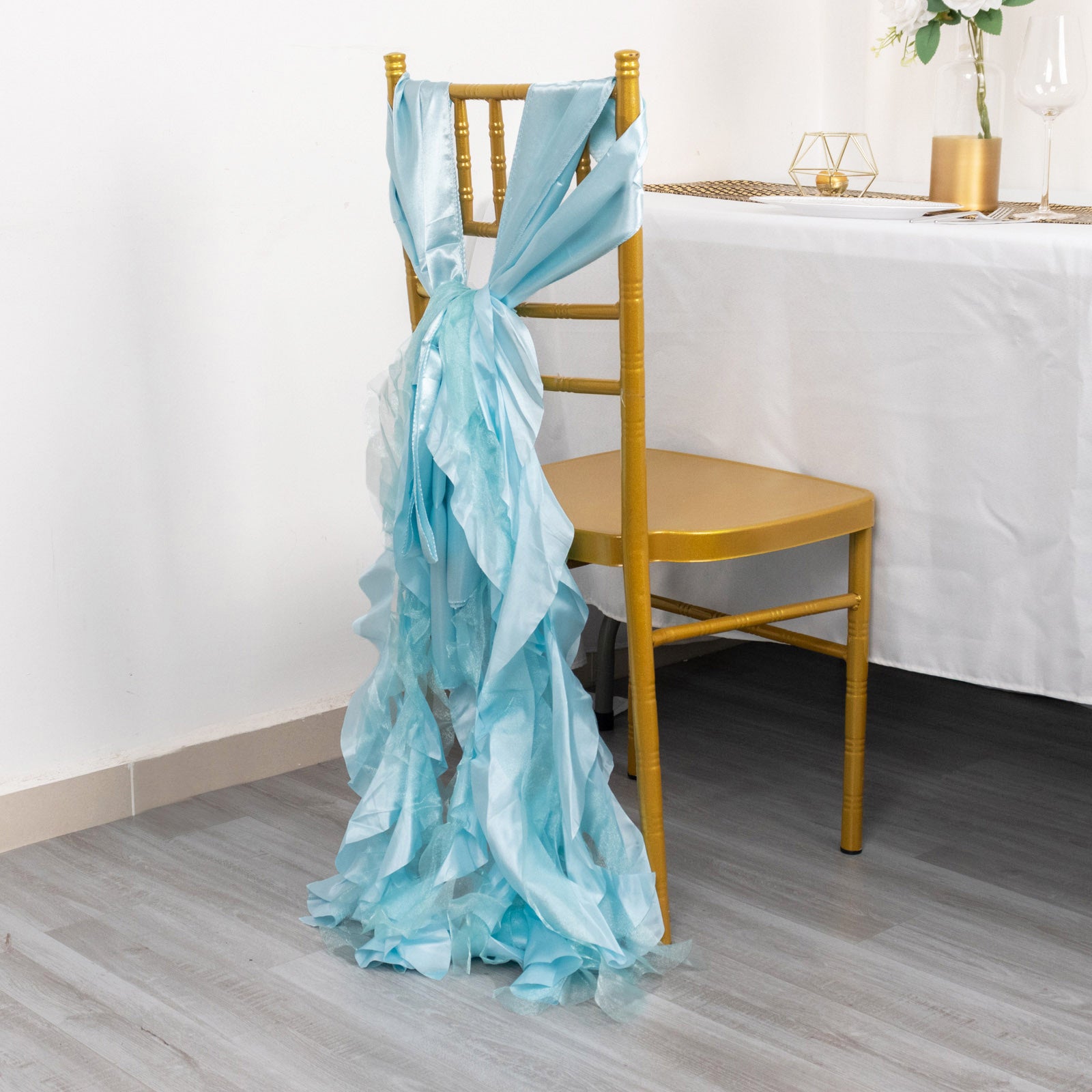 Light blue curly chiffon satin chair sash on a gold chair.