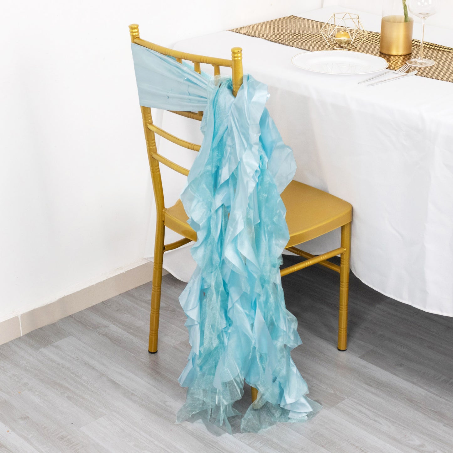 Light blue curly chiffon satin chair sashes draped on a gold chair.