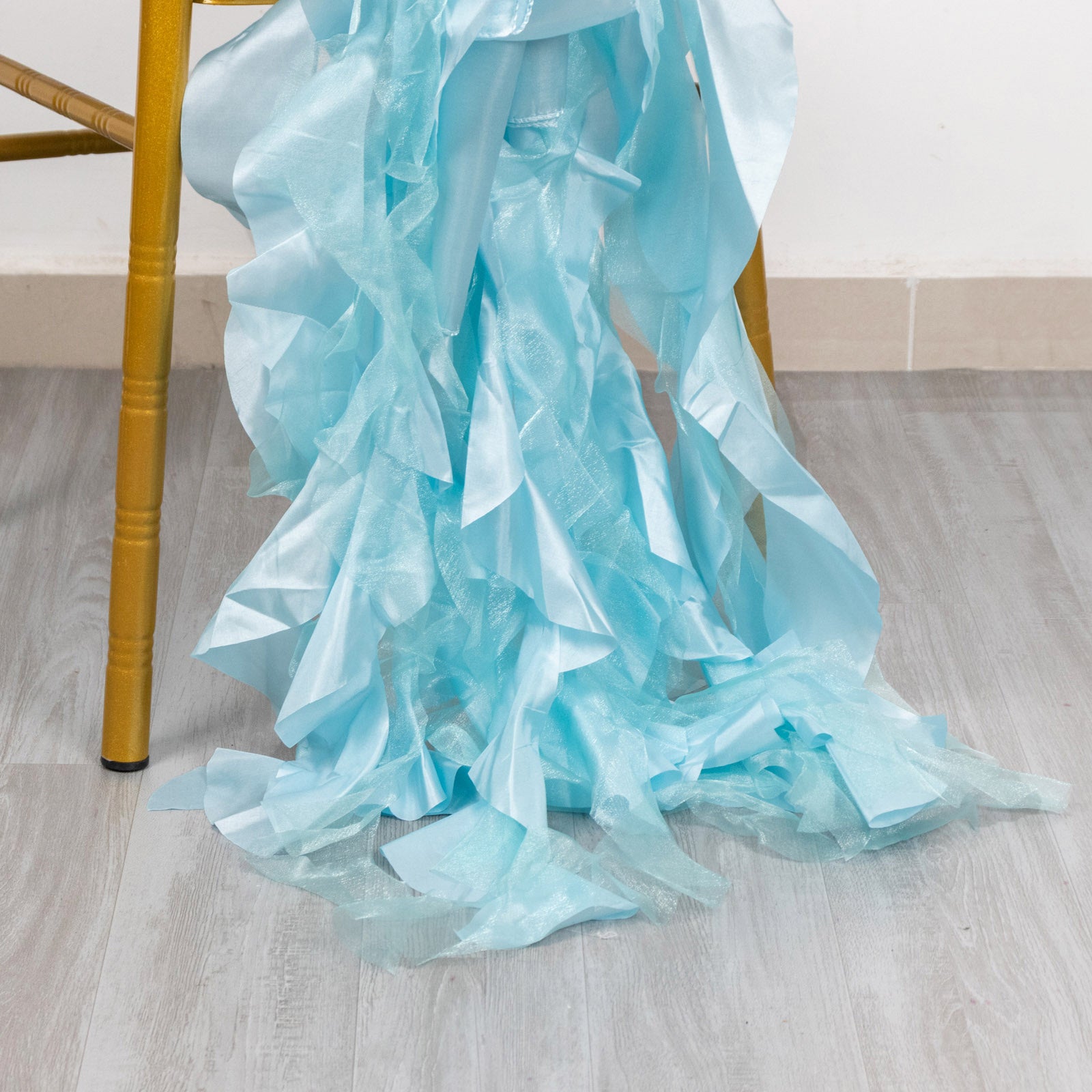 Light blue curly chiffon satin chair sashes draped on a chair.