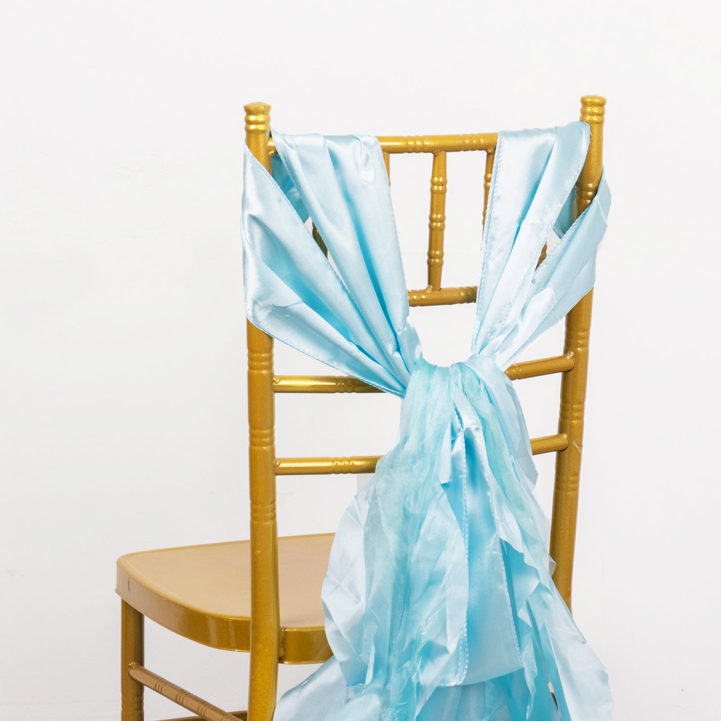 Light blue chiffon satin chair sash tied on a gold chair.