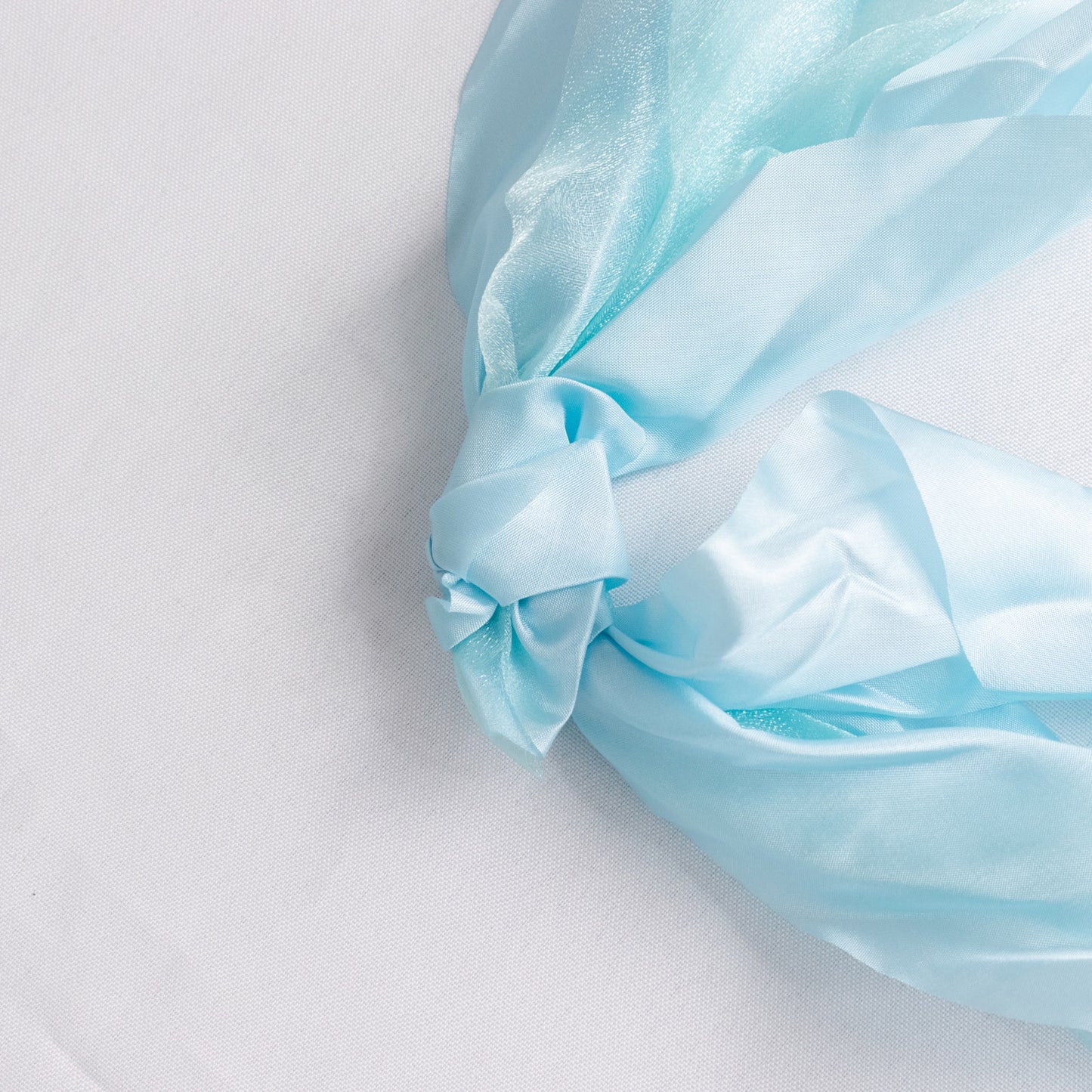 Light blue chiffon satin chair sash tied in a knot.