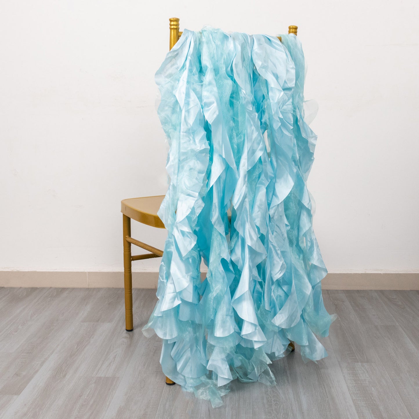Light blue curly chiffon satin chair sashes draped over a gold chair.