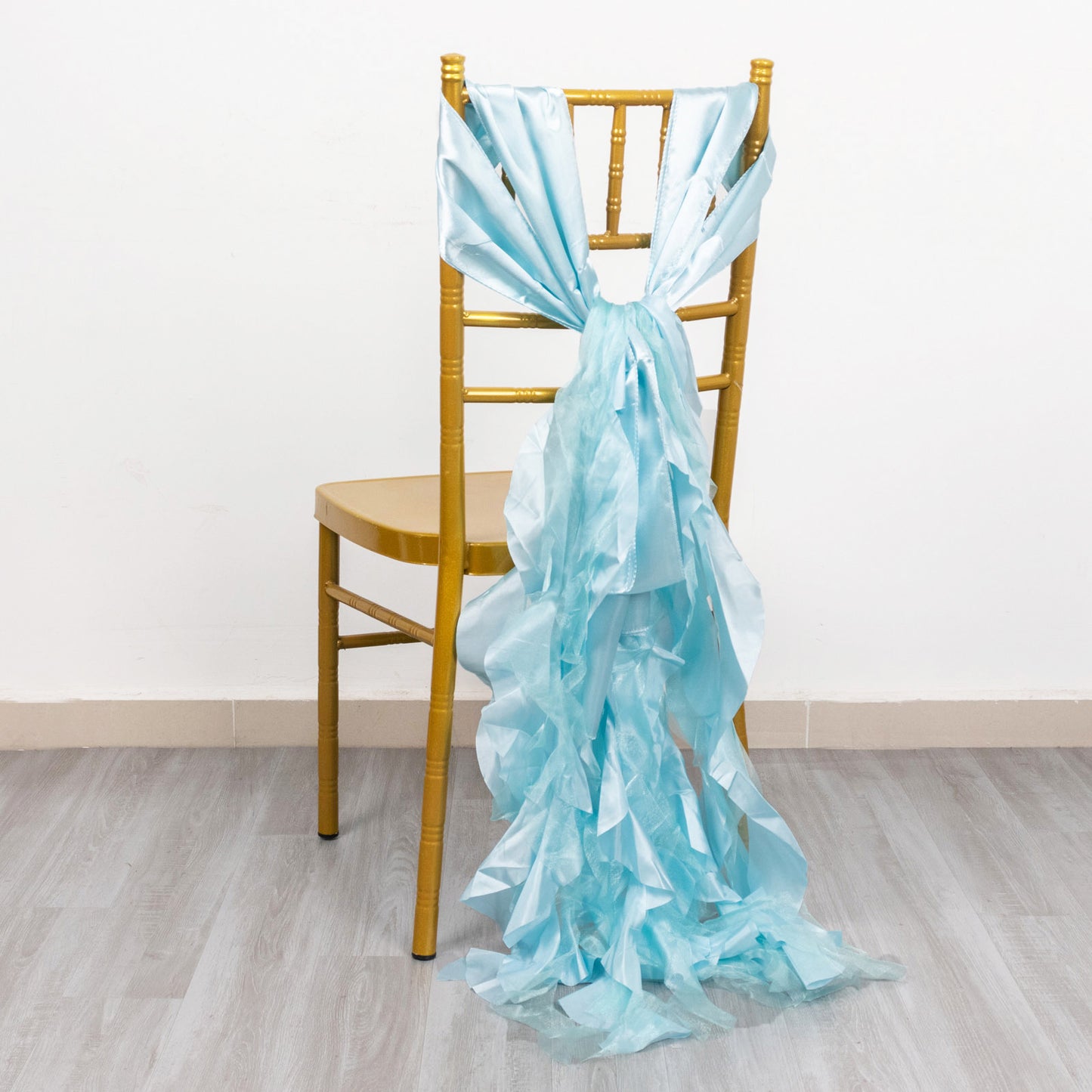 Light blue curly chiffon satin chair sash tied on a gold chair.