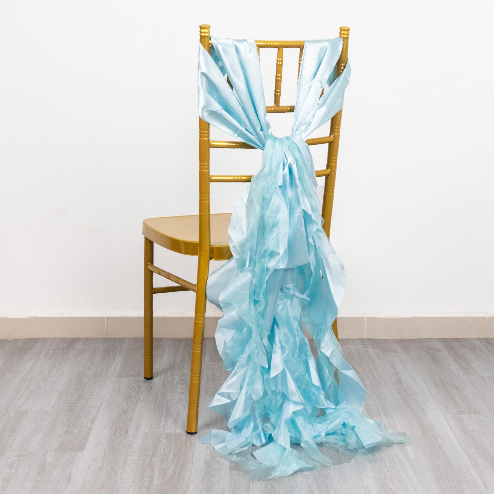 Light blue curly chiffon satin chair sash tied on a gold chair.