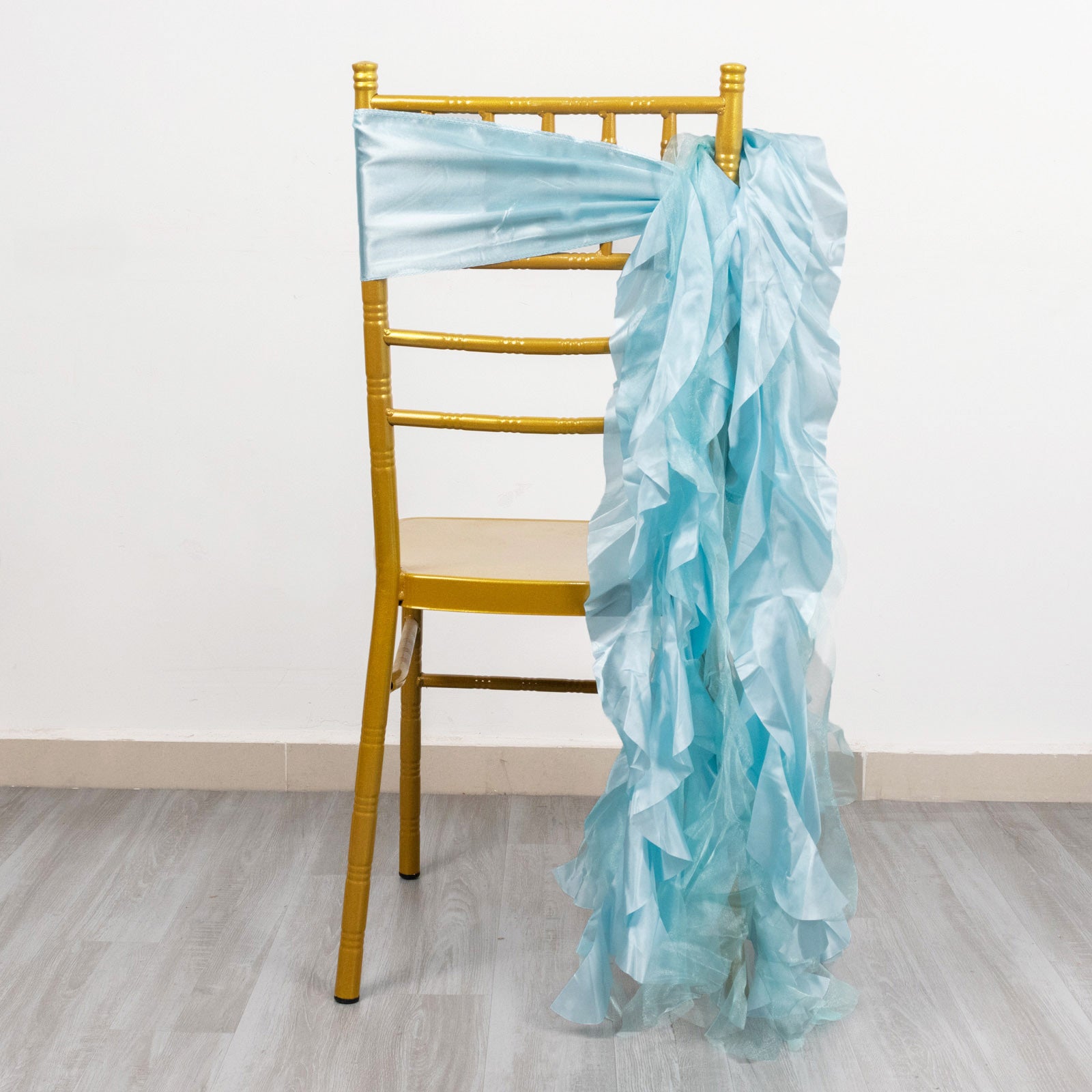 Light blue curly chiffon satin chair sash draped over a gold chair.