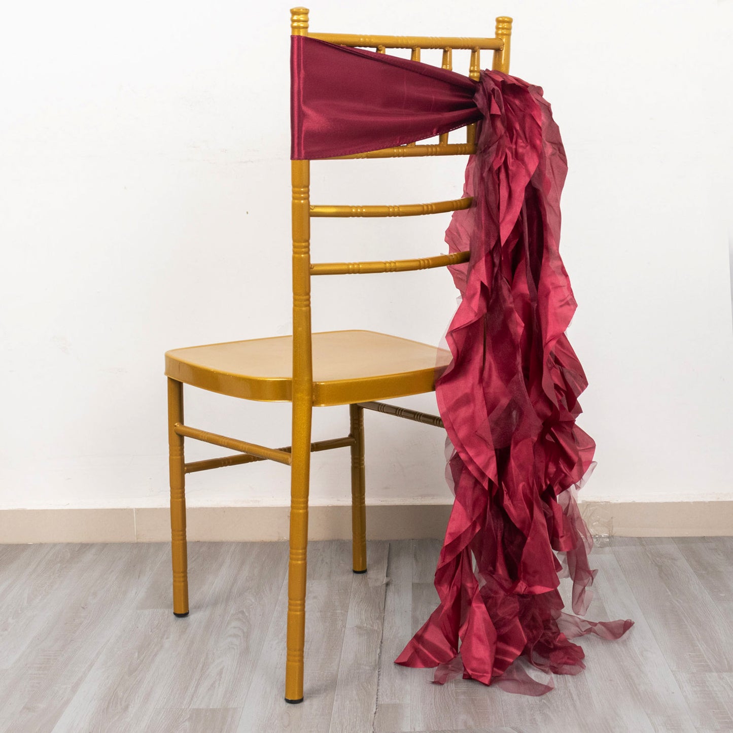 Burgundy chiffon satin chair sash draped on a yellow chair.