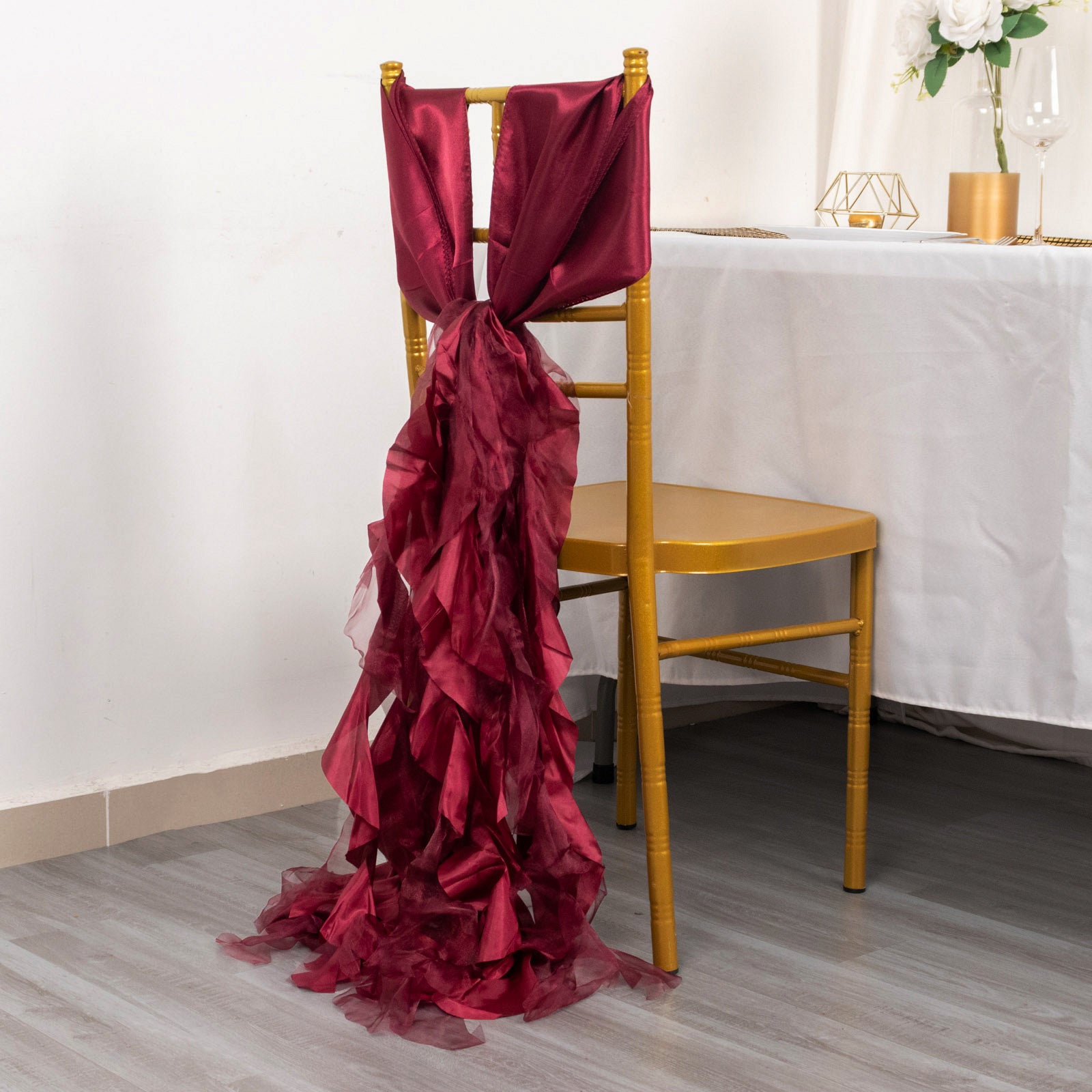 Burgundy chiffon satin chair sash draped over a gold chair.