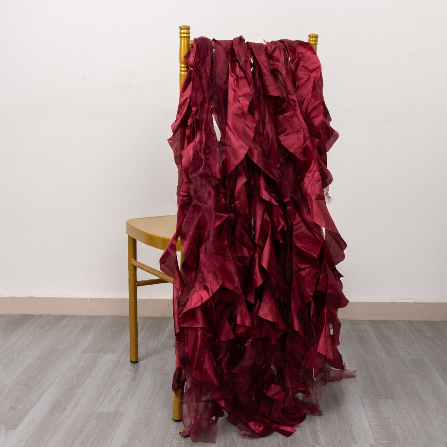 Burgundy curly chiffon satin chair sashes draped over a chair.