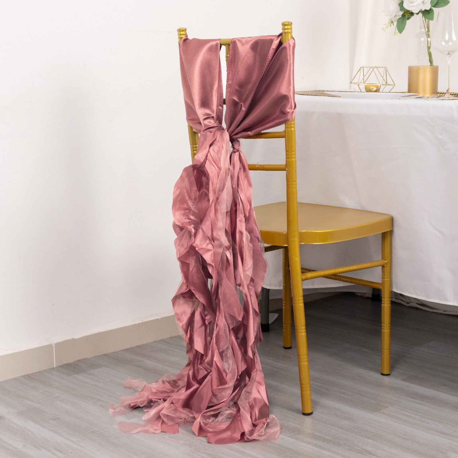 Cinnamon rose chiffon satin chair sash tied on a gold chair.