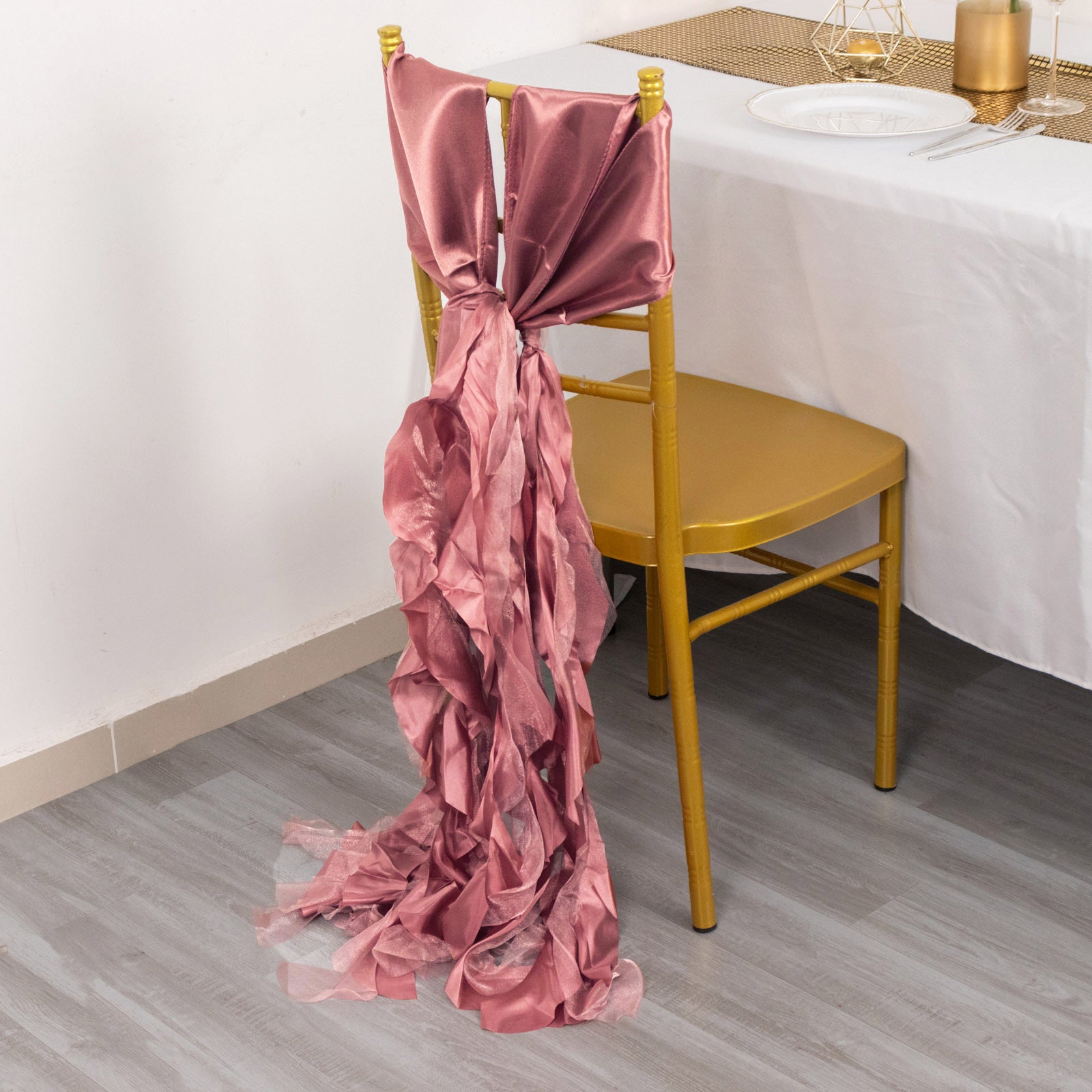 Cinnamon rose chiffon satin chair sash tied on a gold chair.