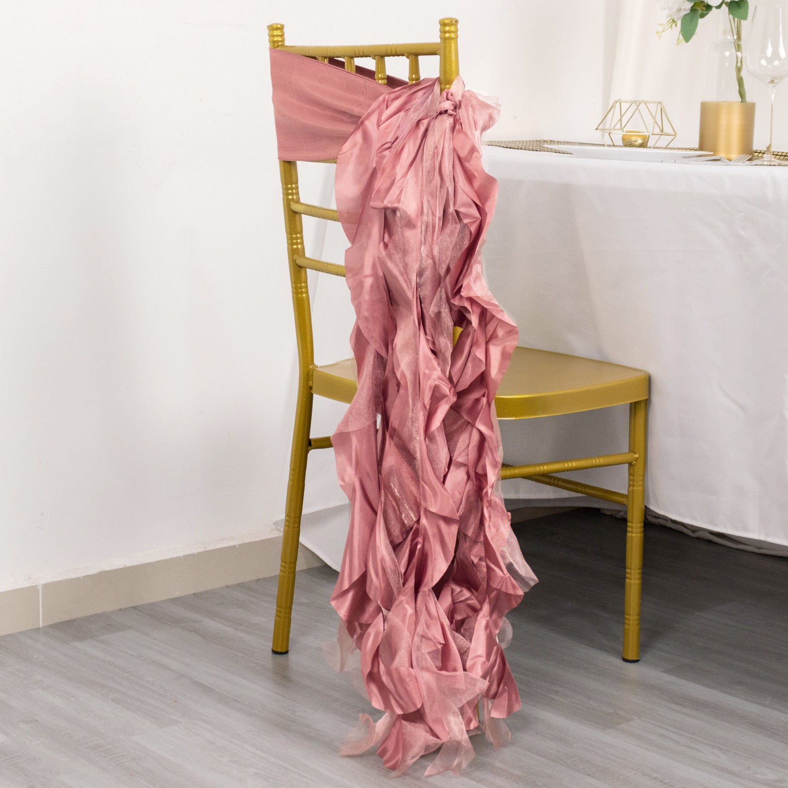 Cinnamon rose chiffon satin chair sash draped on a gold chiavari chair.