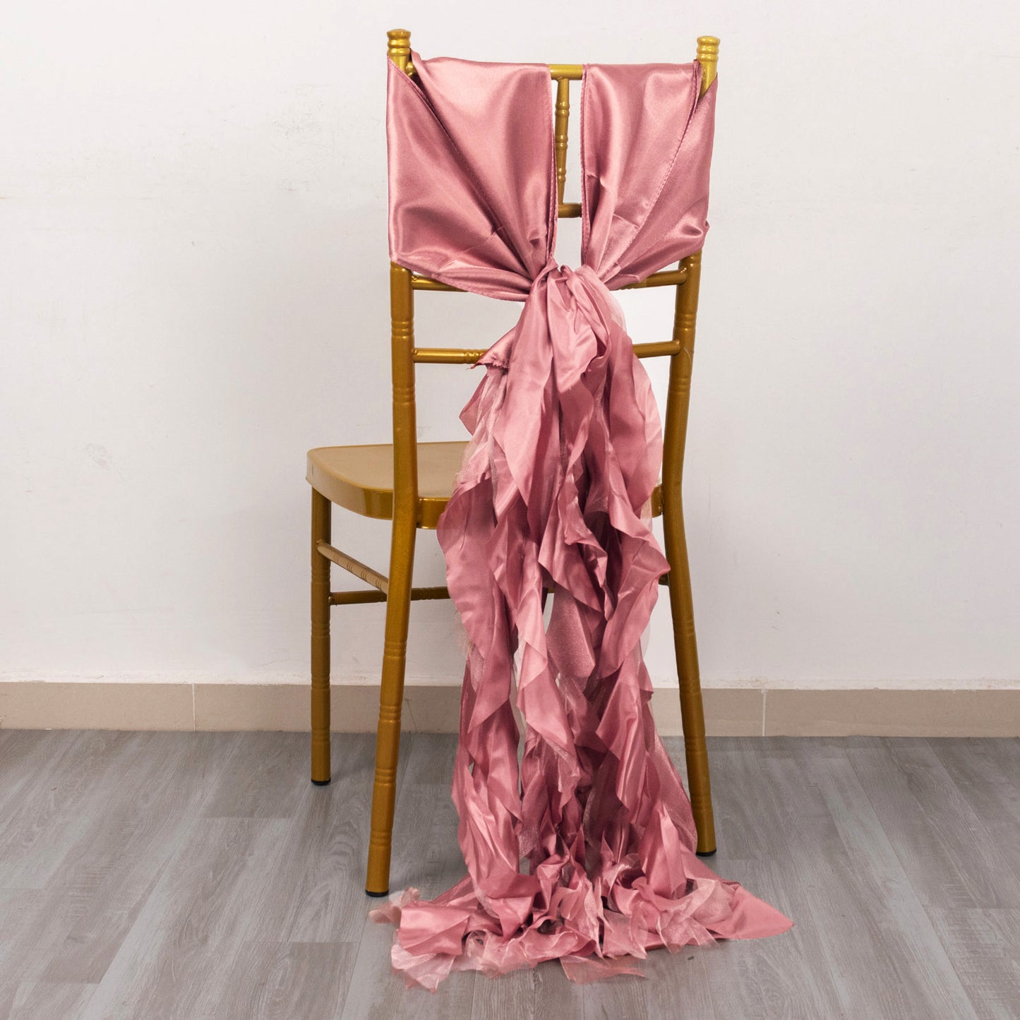 Cinnamon rose chiffon satin chair sash draped on a wooden chair.