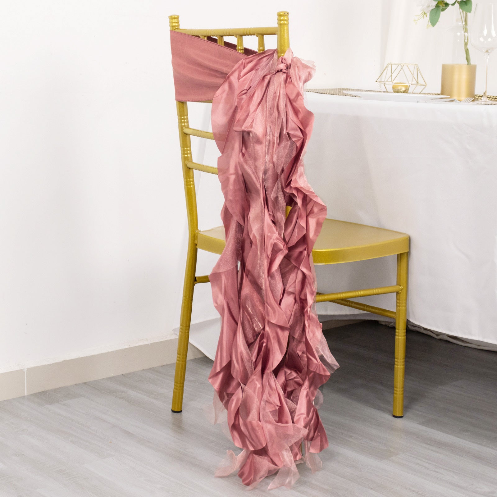 Cinnamon rose chiffon satin chair sash draped on a gold chair.