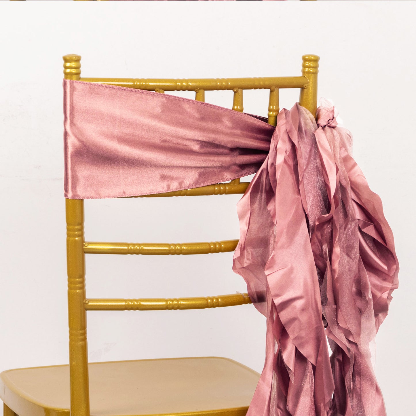 Cinnamon rose satin chair sashes elegantly tied on a gold chair.