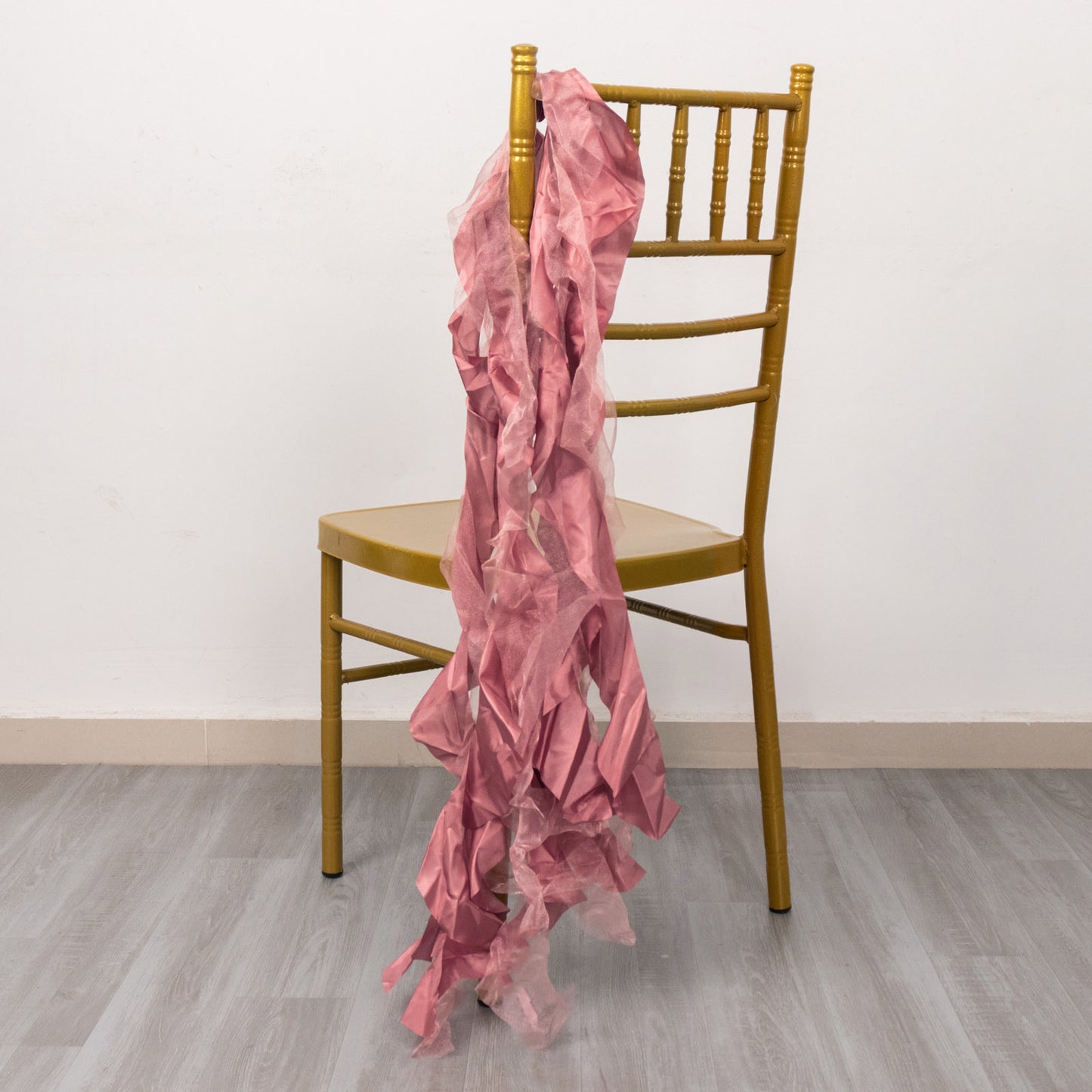 Cinnamon rose chiffon satin chair sash draped over a gold chair.