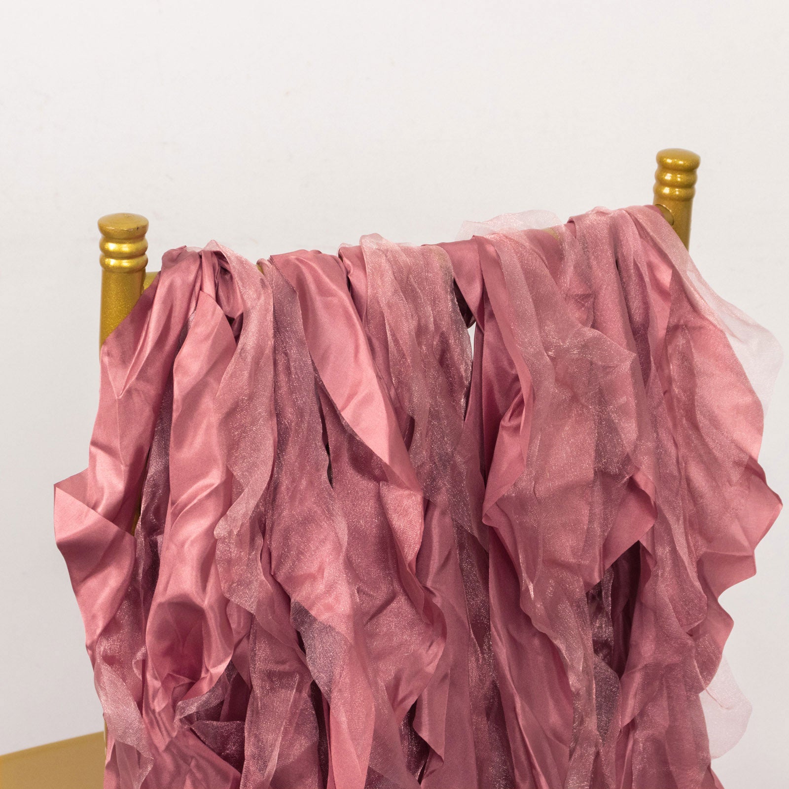 Cinnamon rose chiffon satin chair sashes draped on a gold chair.
