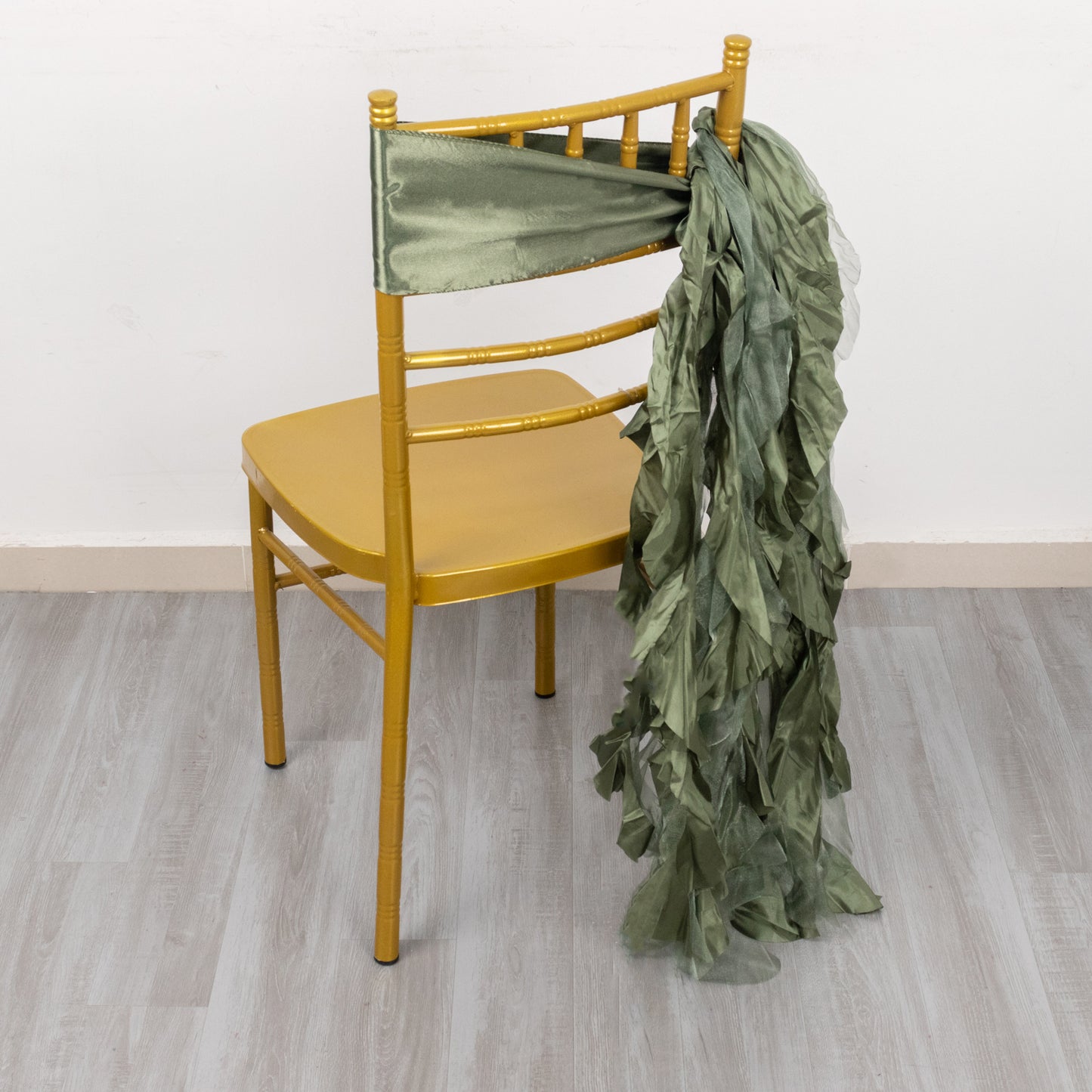 Dusty sage green chiffon satin chair sashes draped on a chair.