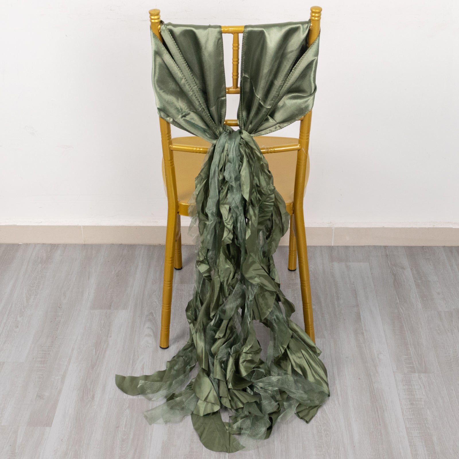 Dusty sage green curly chiffon satin chair sash on a chair.