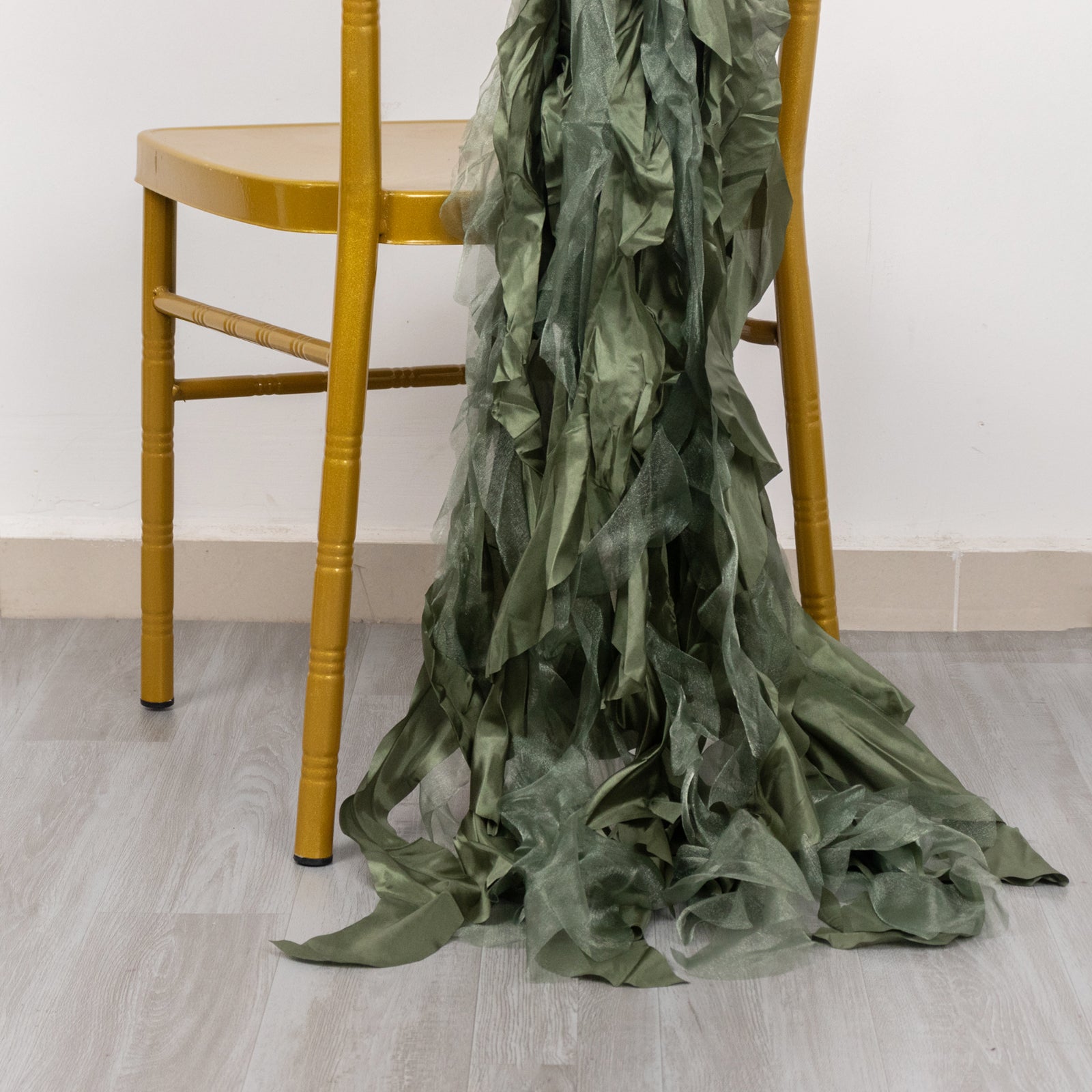 Dusty sage green curly willow chiffon satin chair sash draped on a chair.