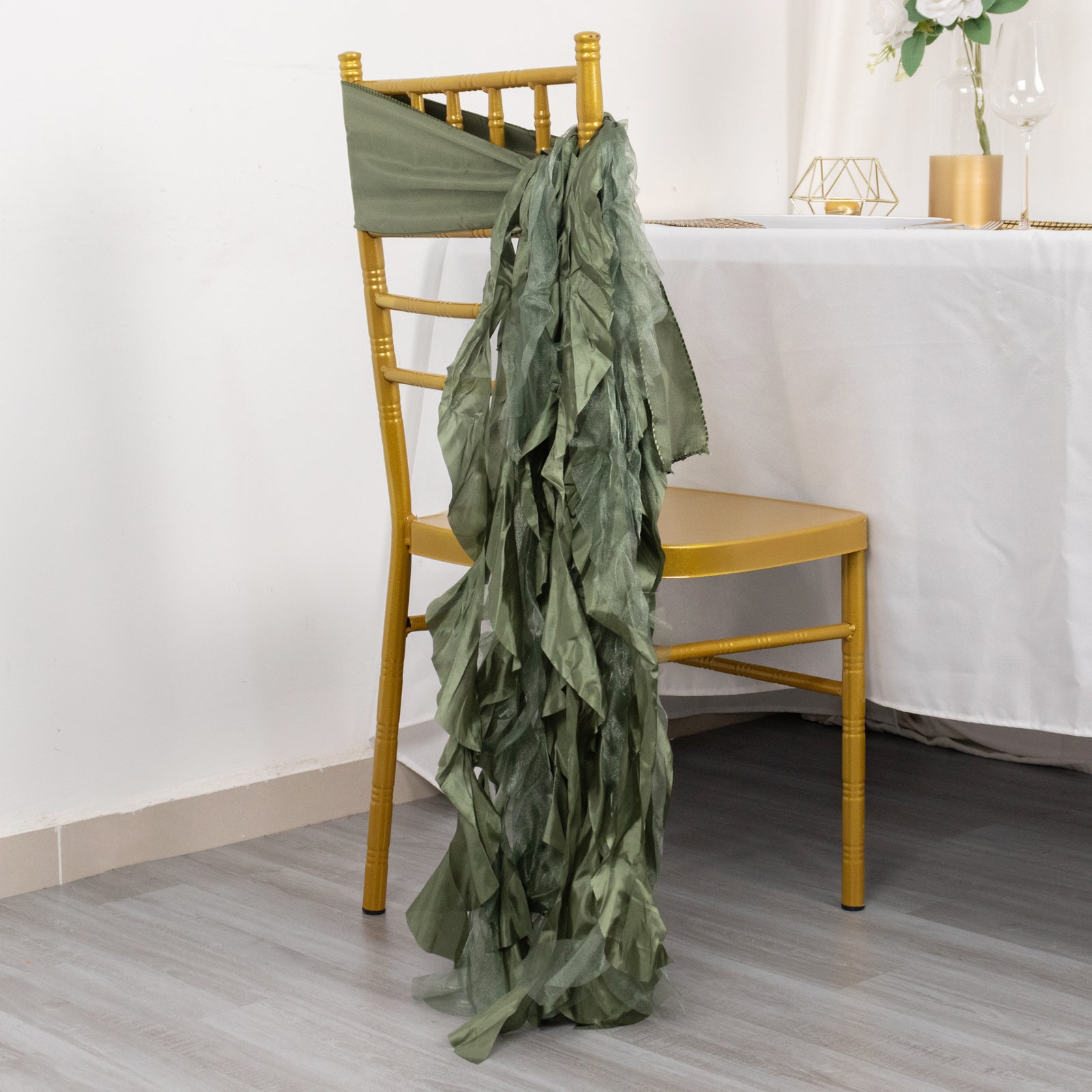 Dusty sage green curly willow chiffon satin chair sash on a gold chair.