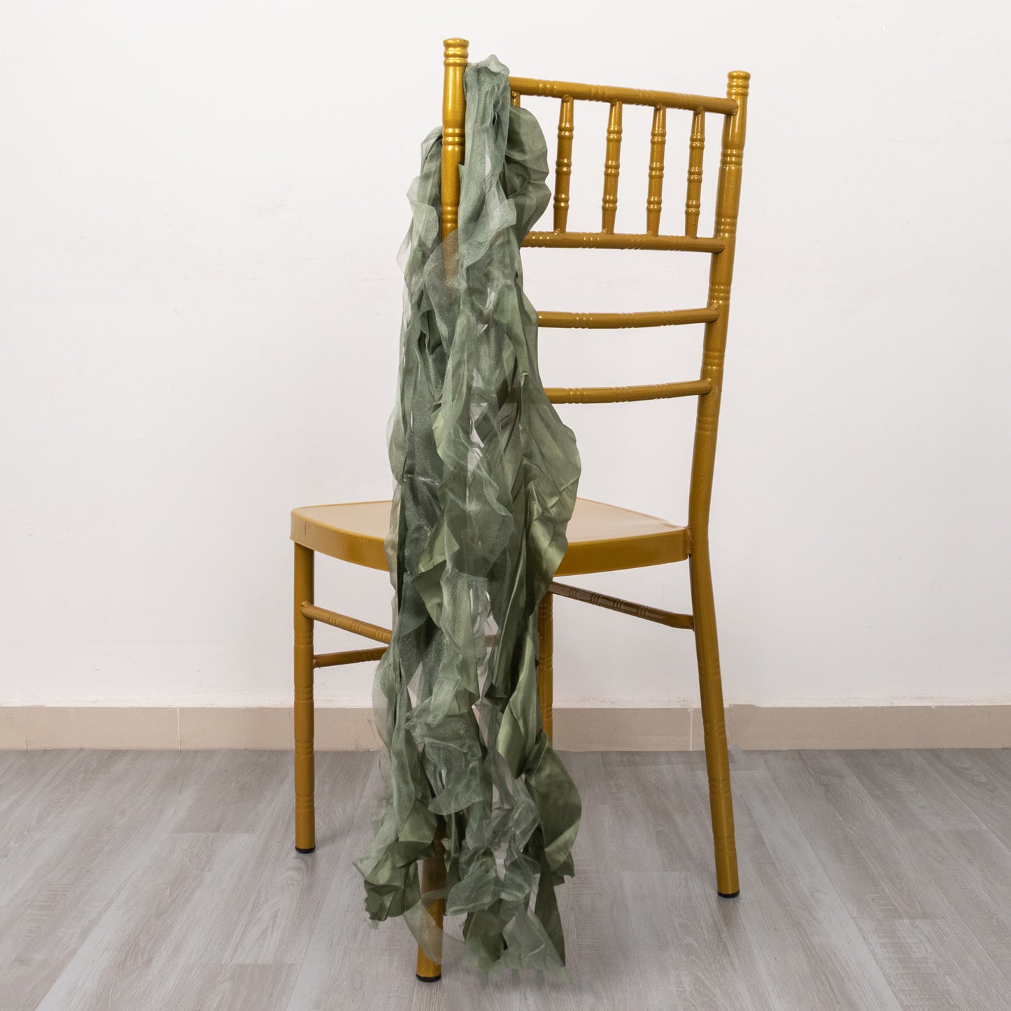 Dusty sage green curly chiffon satin chair sash on a gold chair.