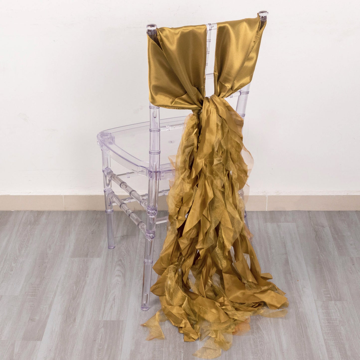 Gold satin chair sash draped on a clear acrylic chair.