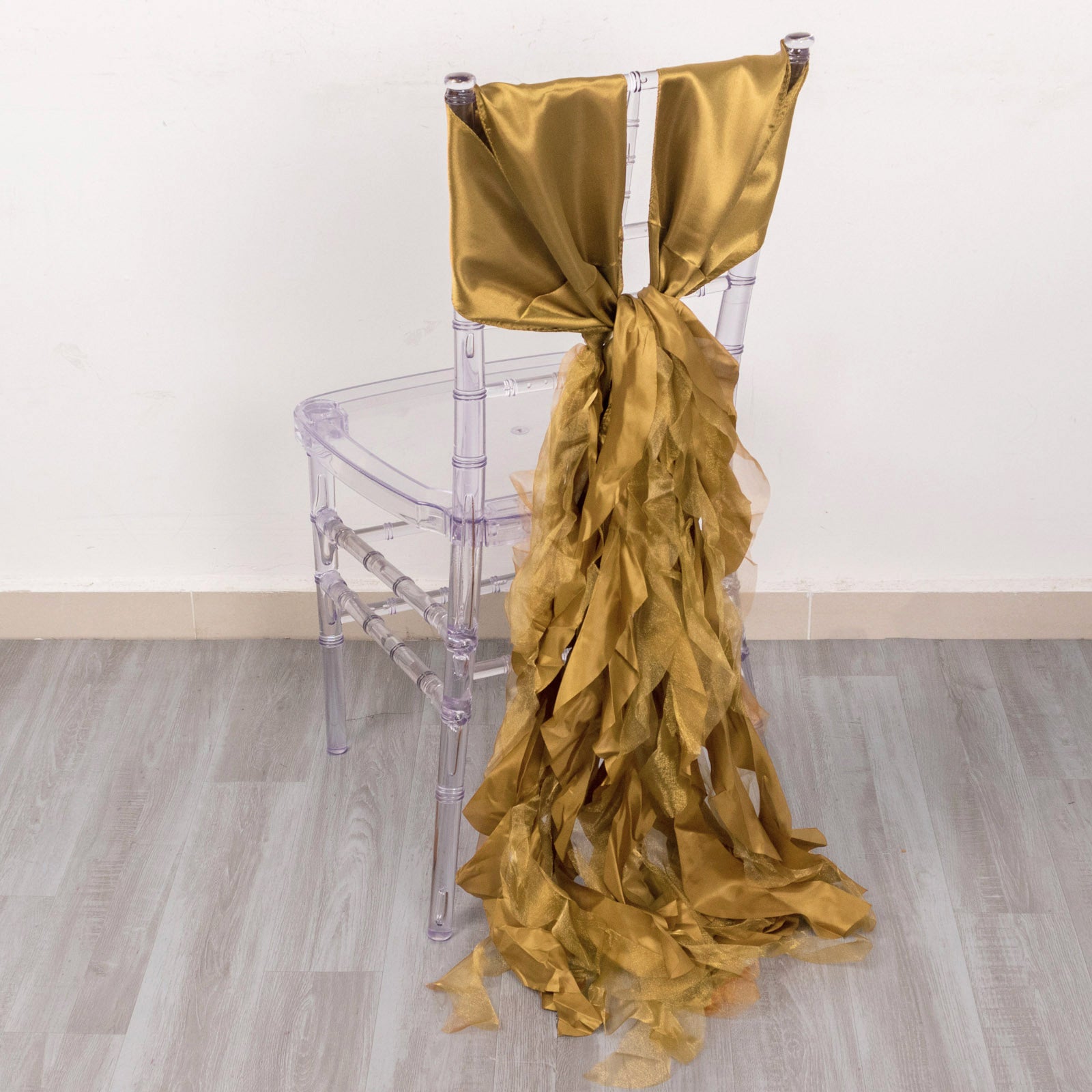 Gold satin chair sash draped on a clear acrylic chair.