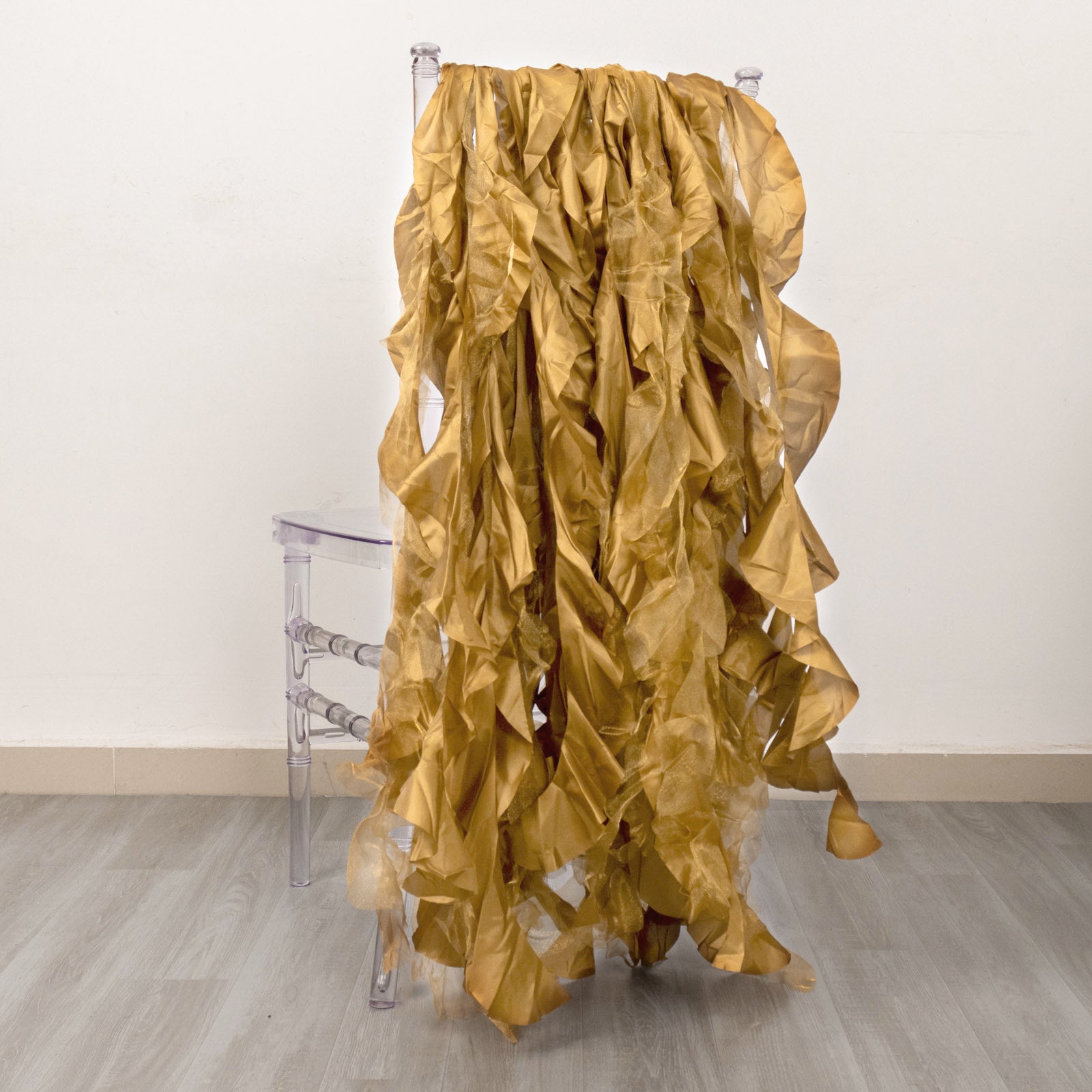 Gold curly chiffon satin chair sashes draped over a clear chair.