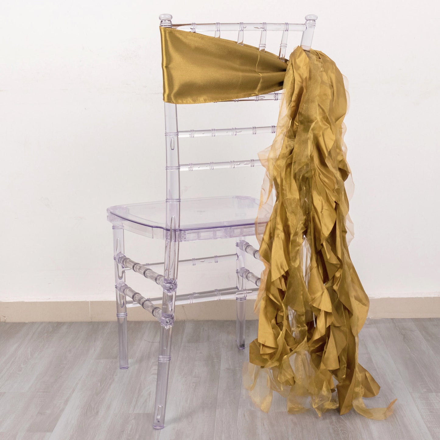 Gold chiffon satin chair sashes draped on a clear chiavari chair.
