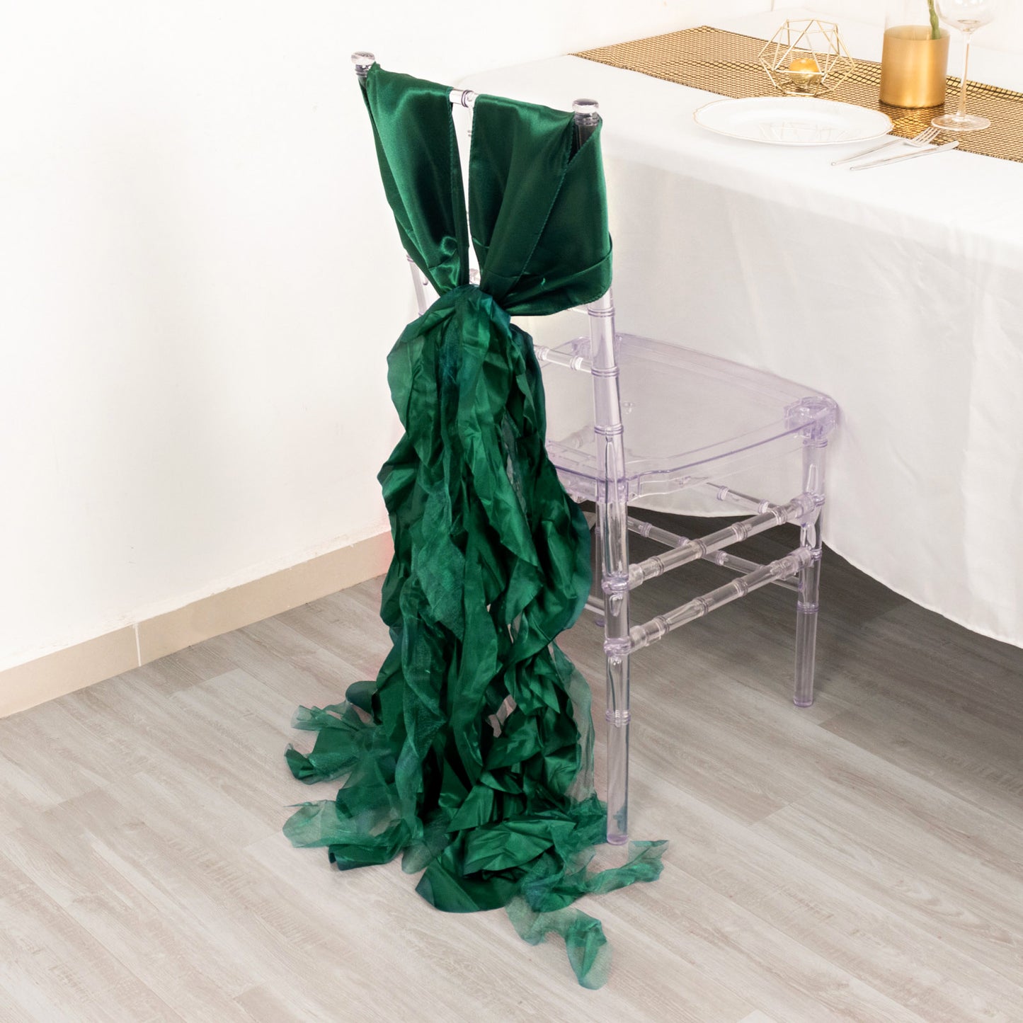 Emerald green chiffon satin chair sash draped on a clear chair.