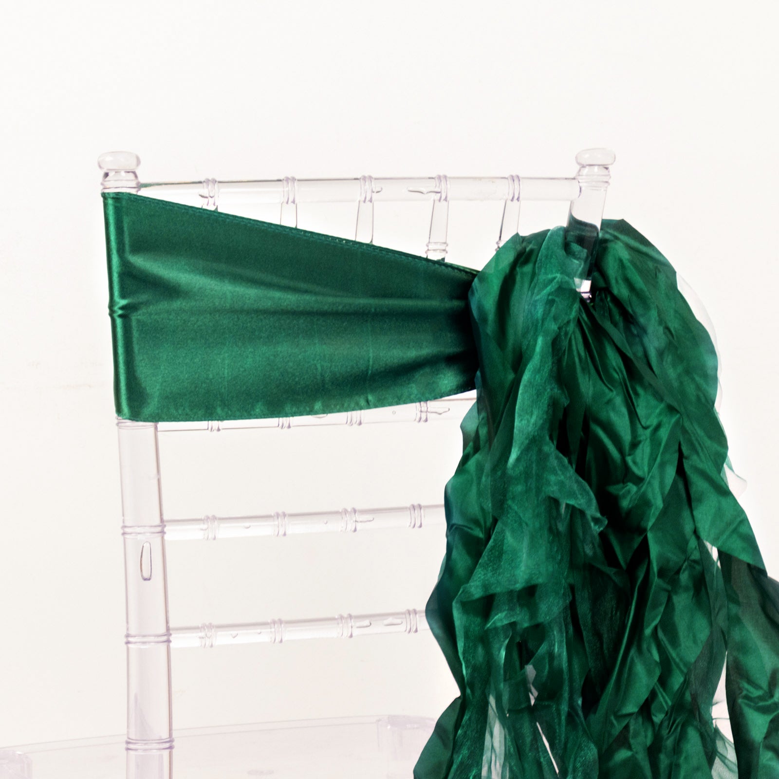 Emerald green curly chiffon satin chair sash on a clear chair.