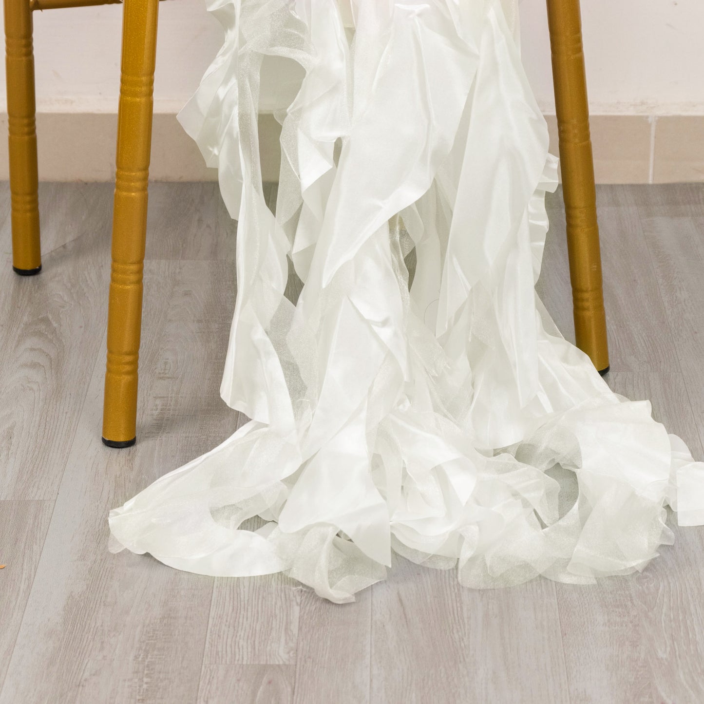 Ivory curly chiffon satin chair sashes draping over a chair leg.