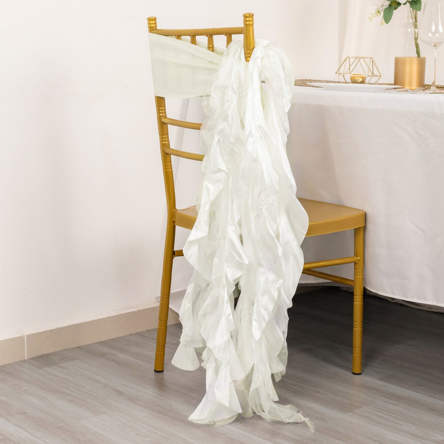 Ivory curly chiffon satin chair sash draped on a gold chiavari chair.