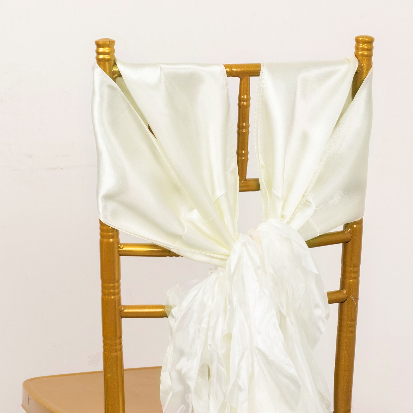 Ivory satin chair sashes tied on a gold chair.