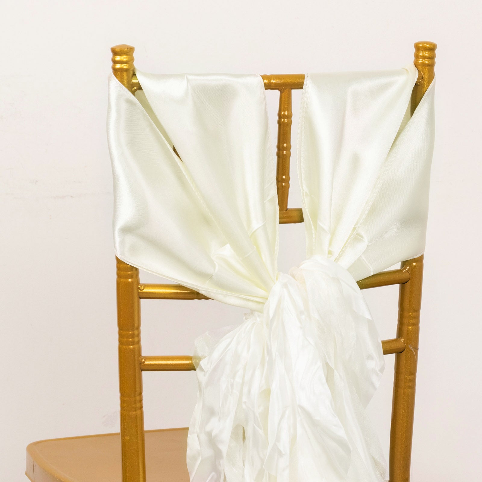 Ivory satin chair sashes tied on a gold chair.
