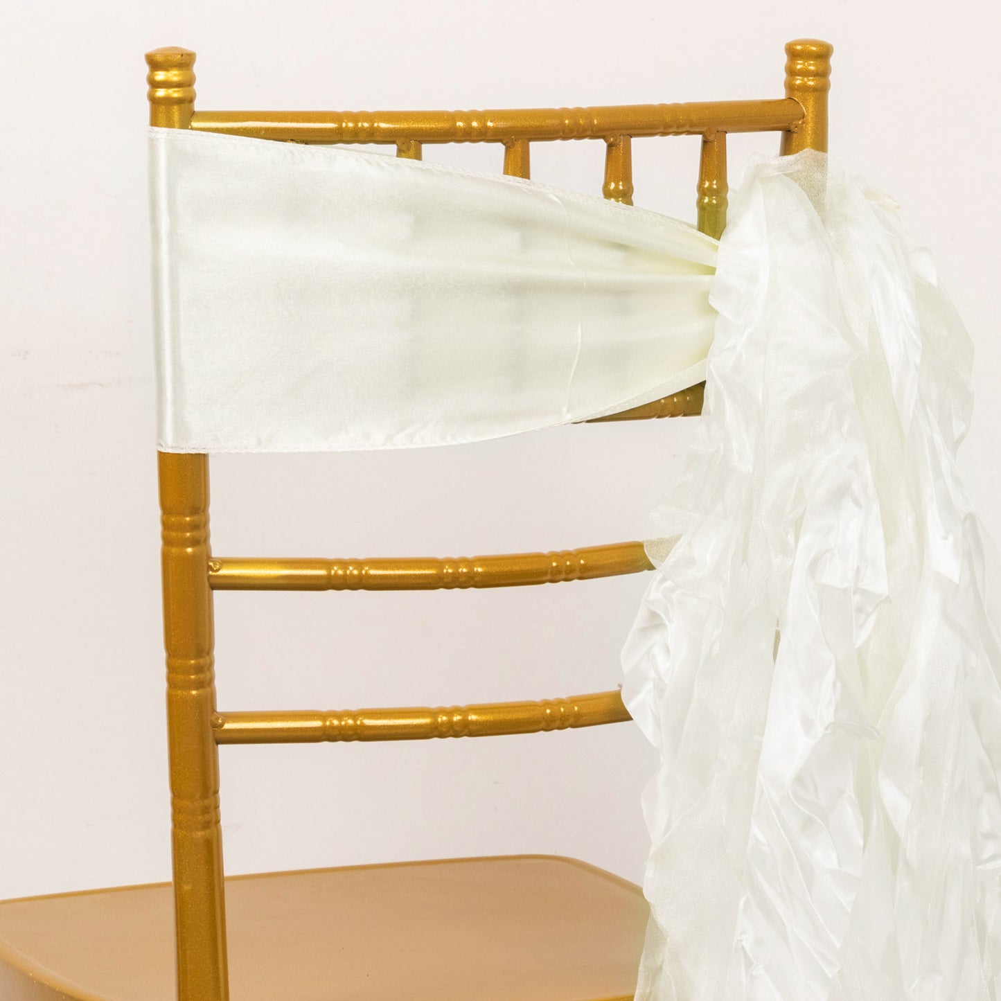 Ivory curly willow chiffon satin chair sashes on a gold chair.