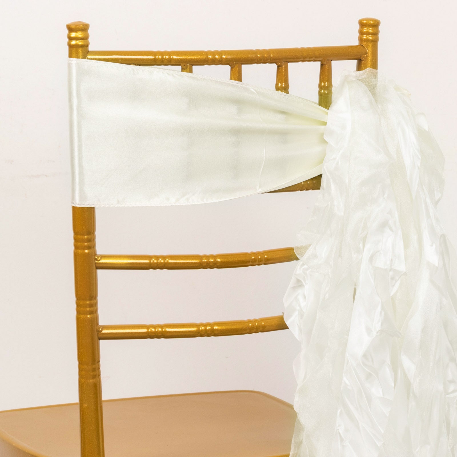 Ivory curly willow chiffon satin chair sashes on a gold chair.