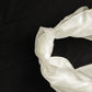 Ivory chiffon satin chair sash tied in a knot on a black background.