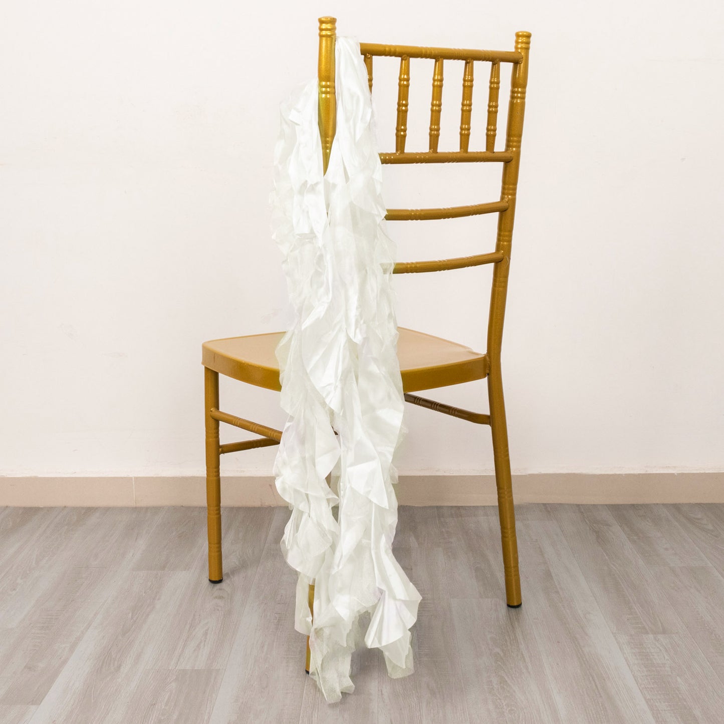 Ivory curly chiffon satin chair sash draped over a golden chair.