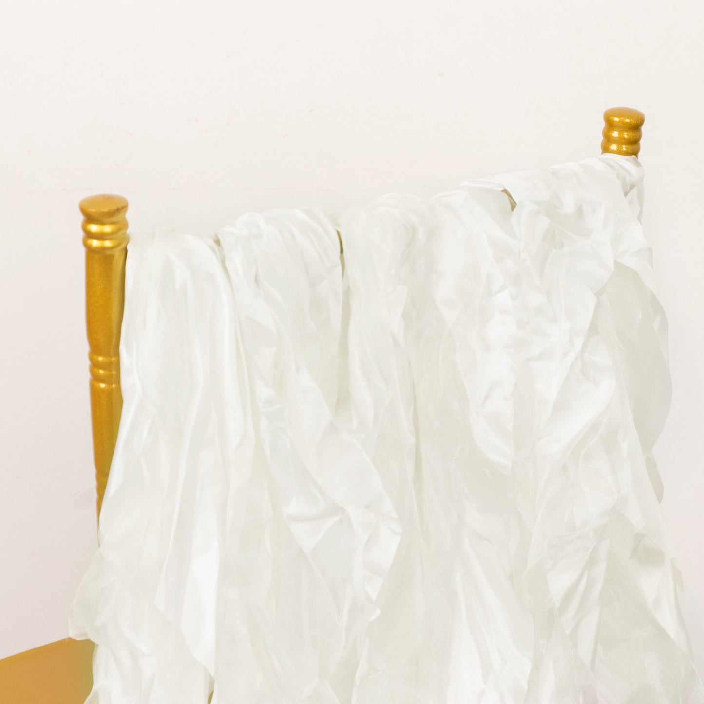 Ivory chiffon satin chair sashes draped over a gold chair.