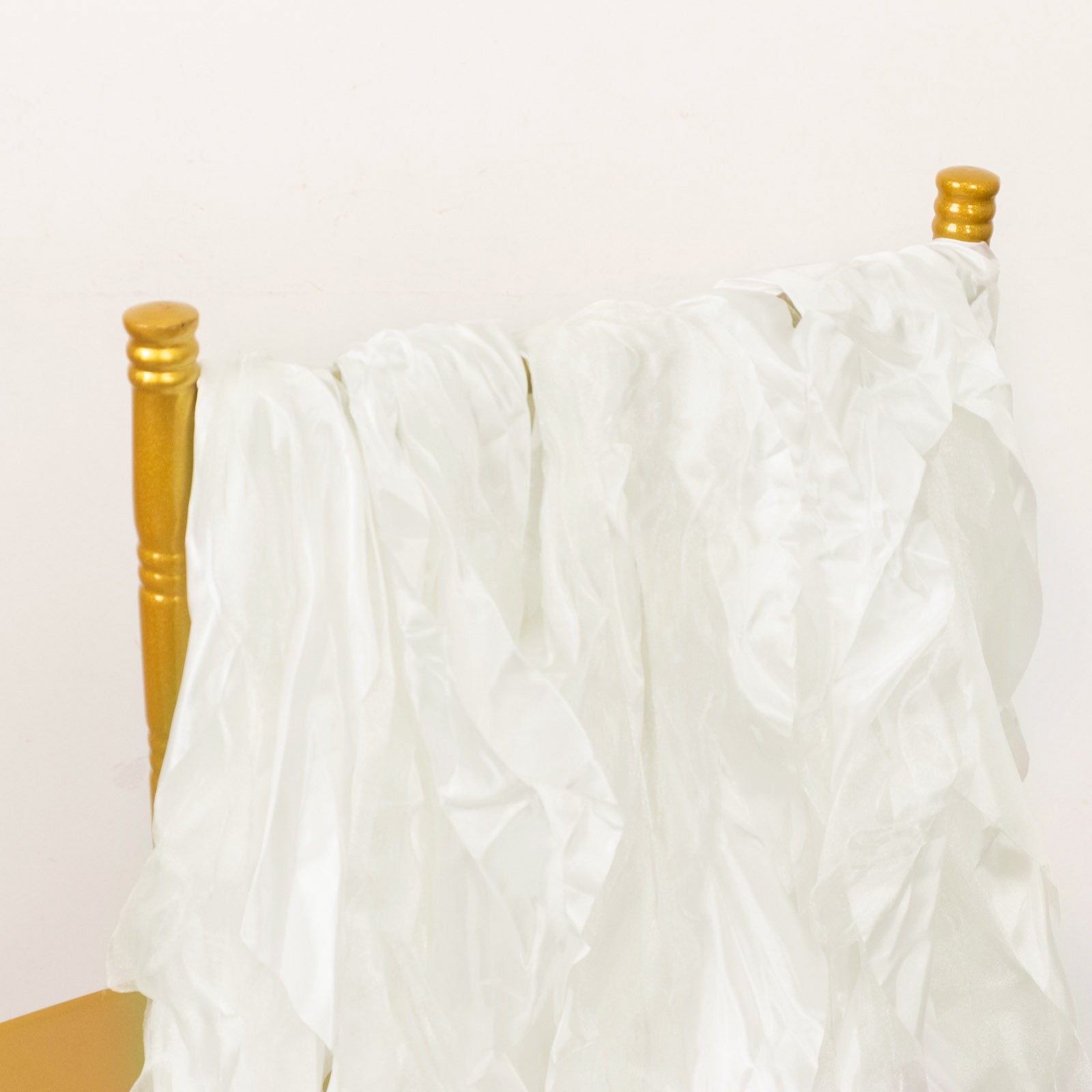 Ivory chiffon satin chair sashes draped over a gold chair.
