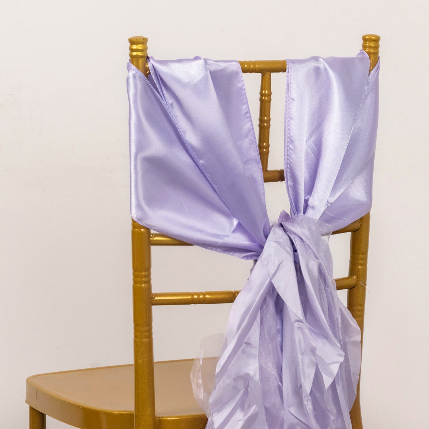 Lavender satin chair sashes draped on a gold chair.
