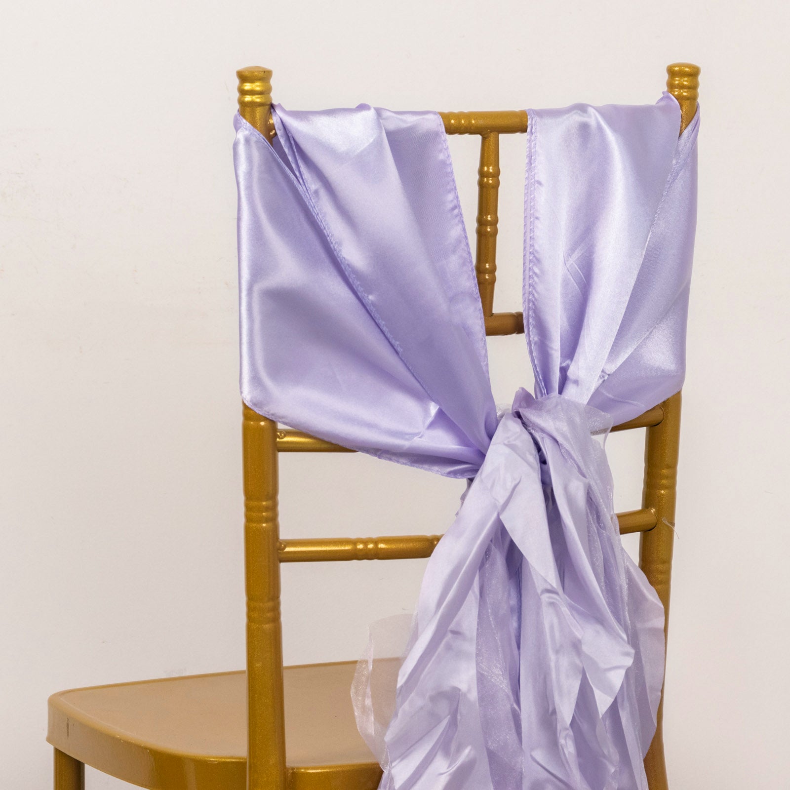 Lavender satin chair sashes draped on a gold chair.