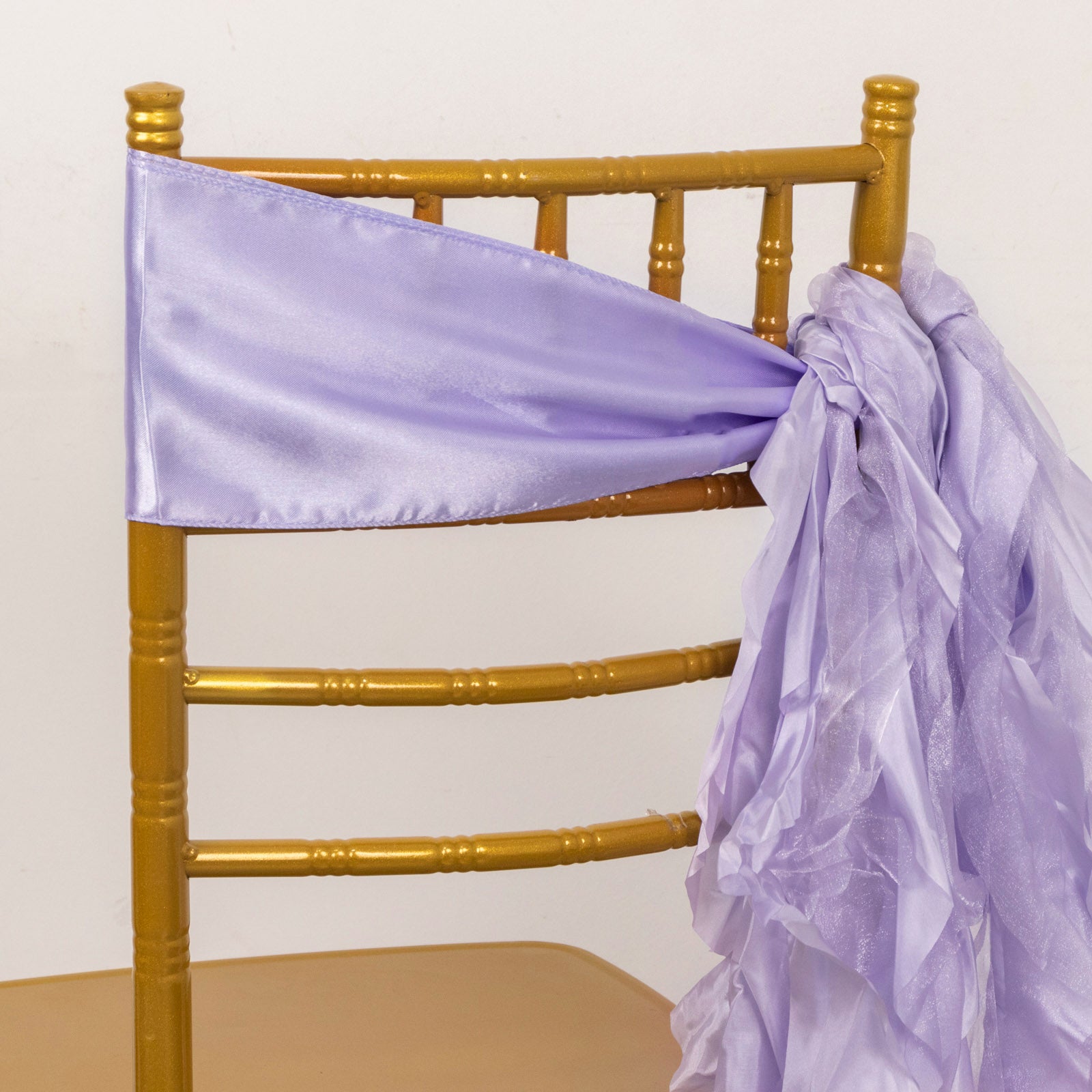 Lavender lilac chiffon satin chair sashes on a gold chair.