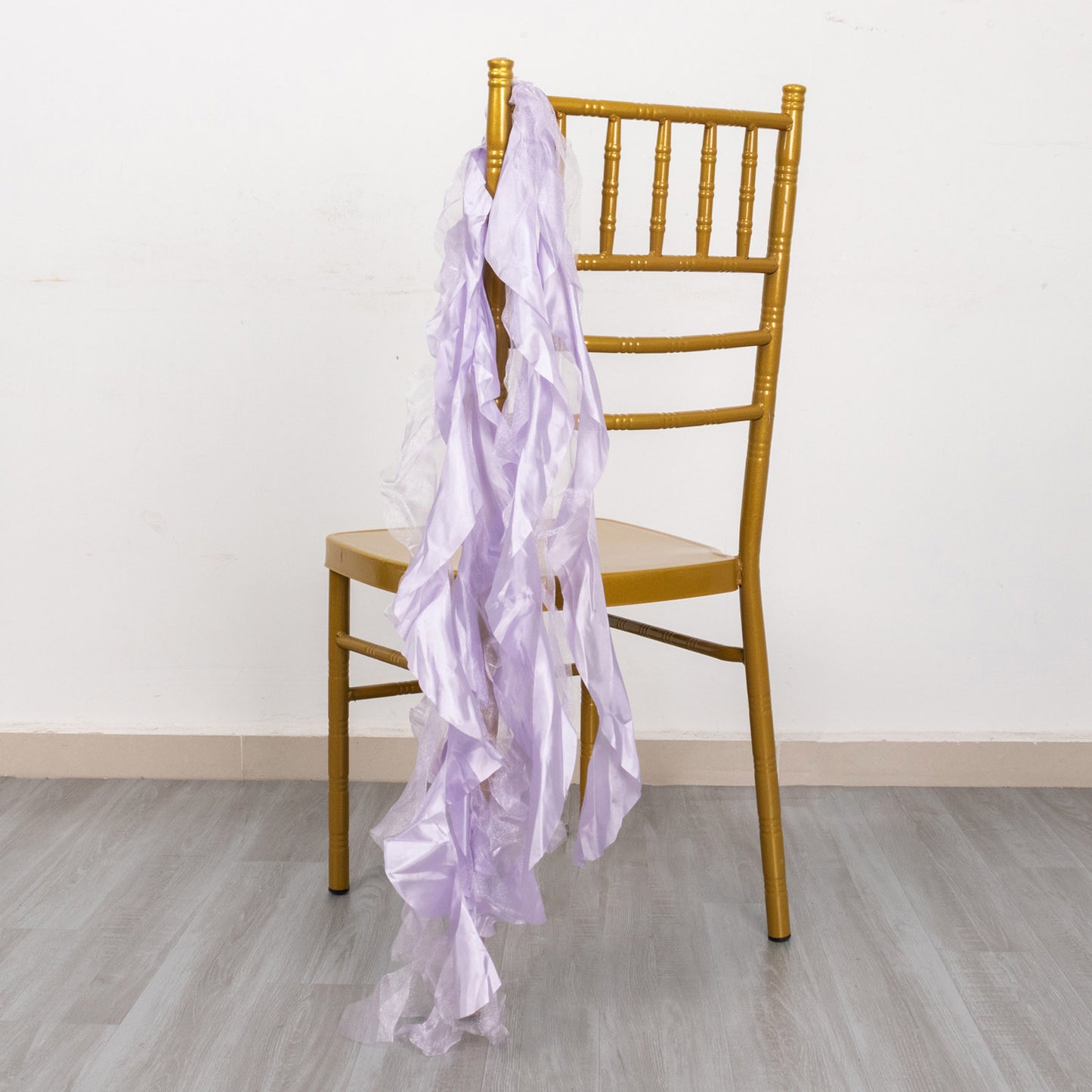 Lavender lilac chiffon satin chair sashes draped over a gold chiavari chair.